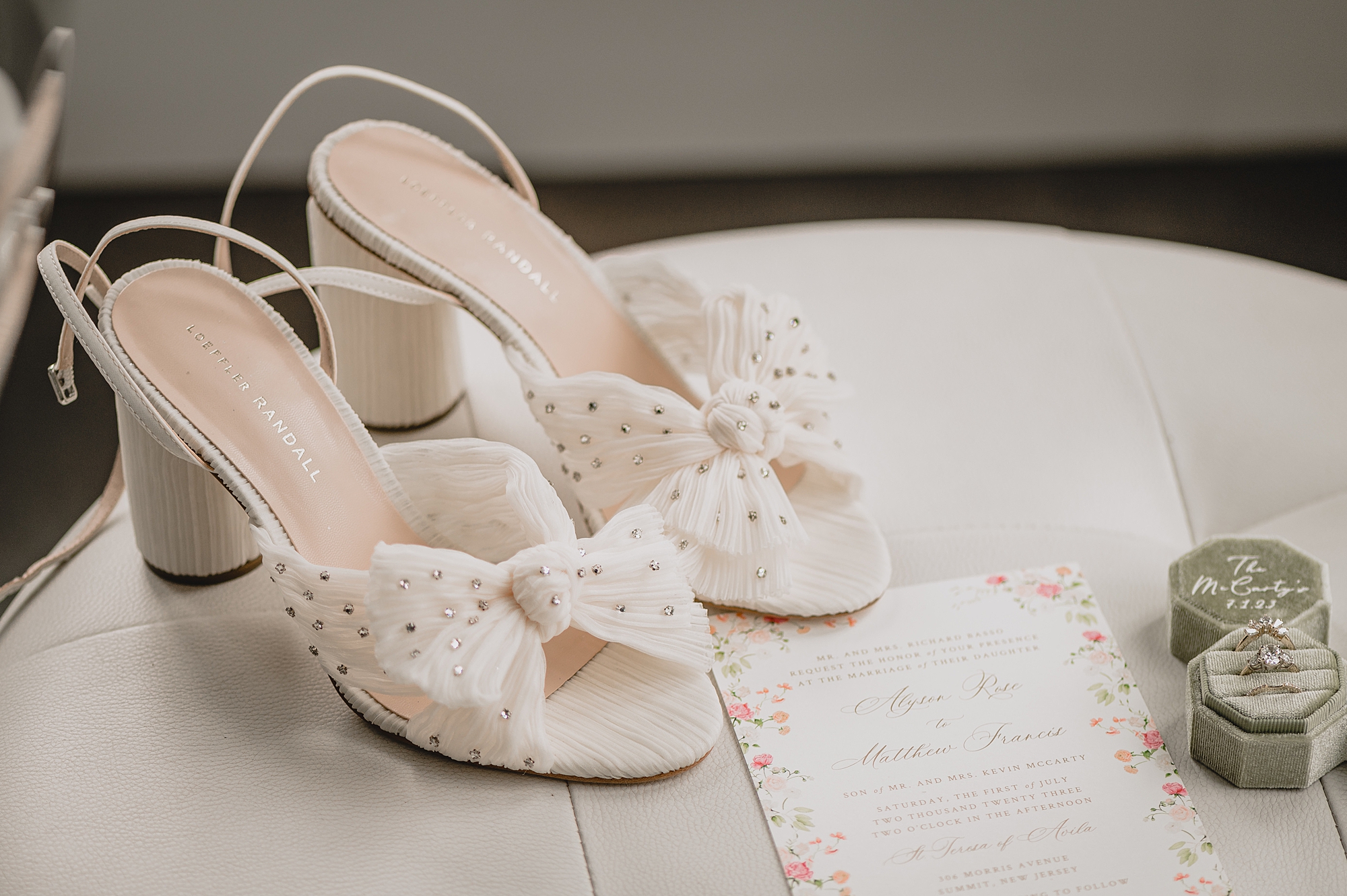 bride's shoes on table with invitation suite with pink flowers