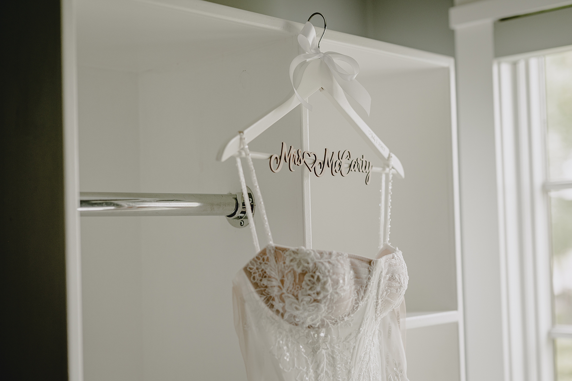 wedding dress hangs on custom hanger with bride's last name