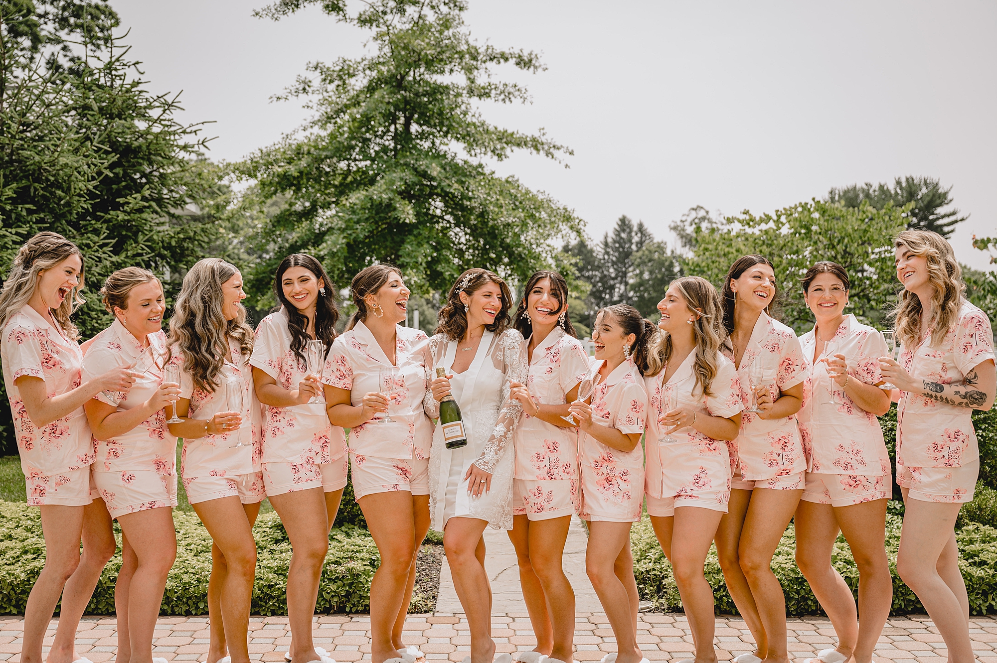 bride poses with bridesmaids in matching pink floral robes