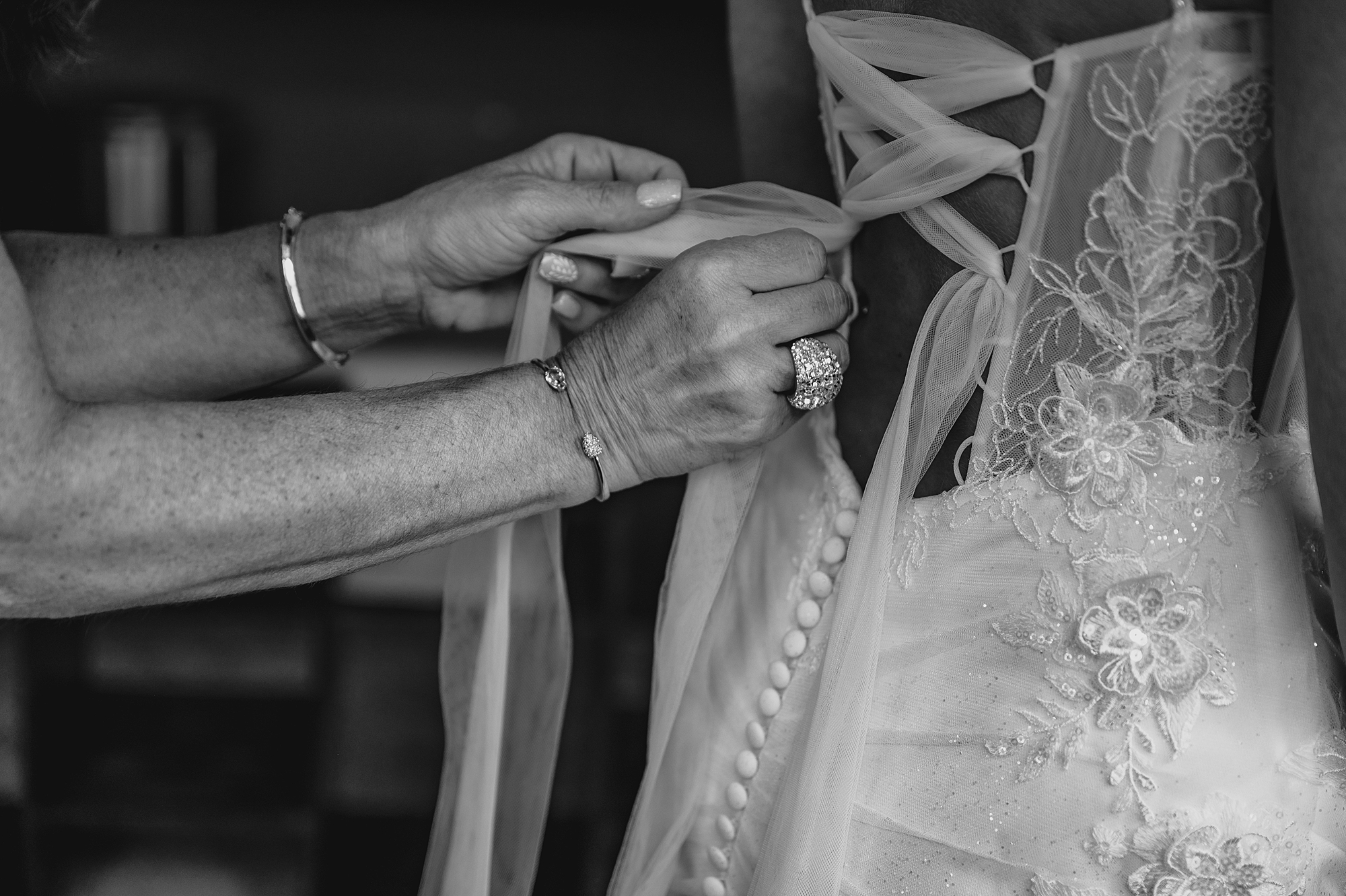 woman laces up black of wedding gown