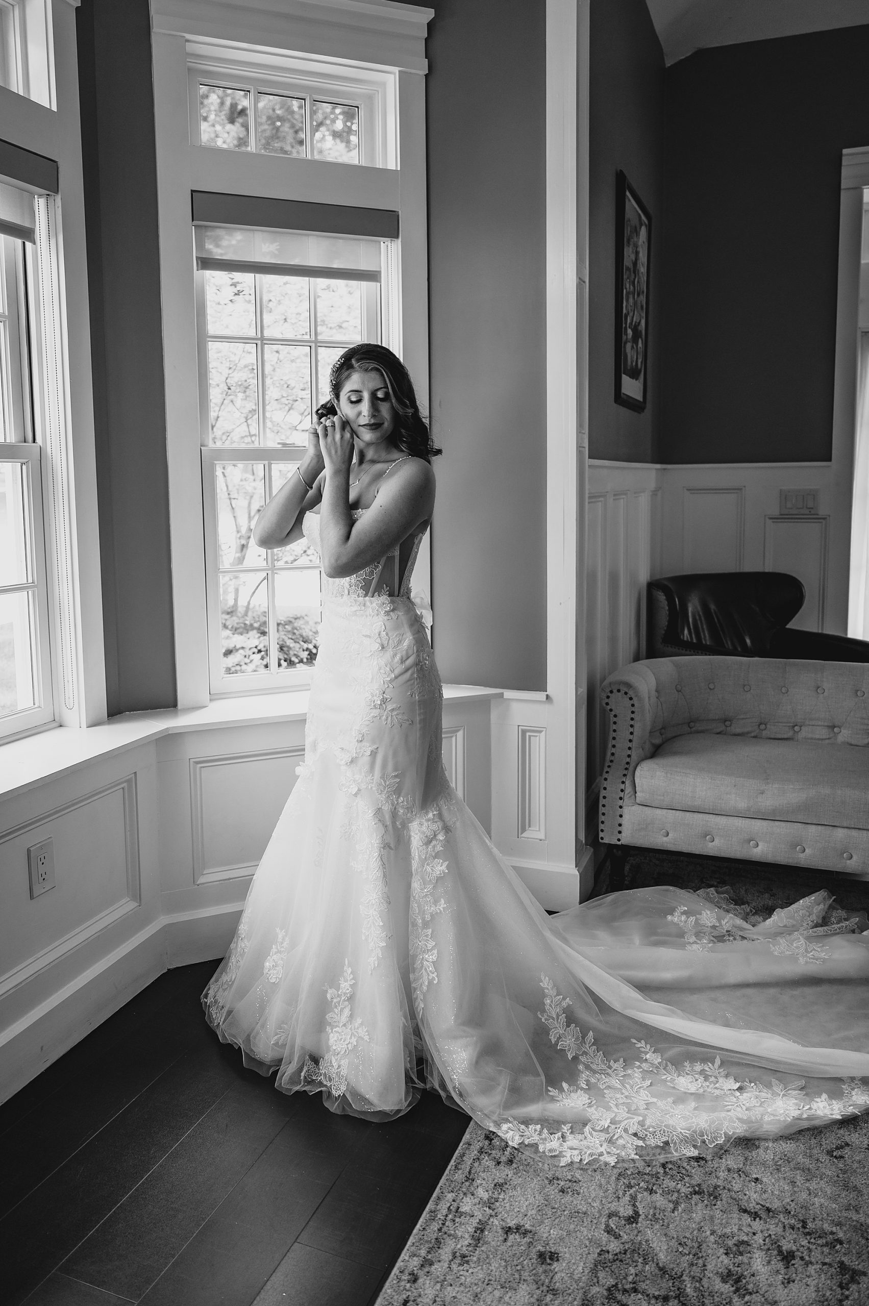 bride stands in window at the Ryland Inn adjusting earrings