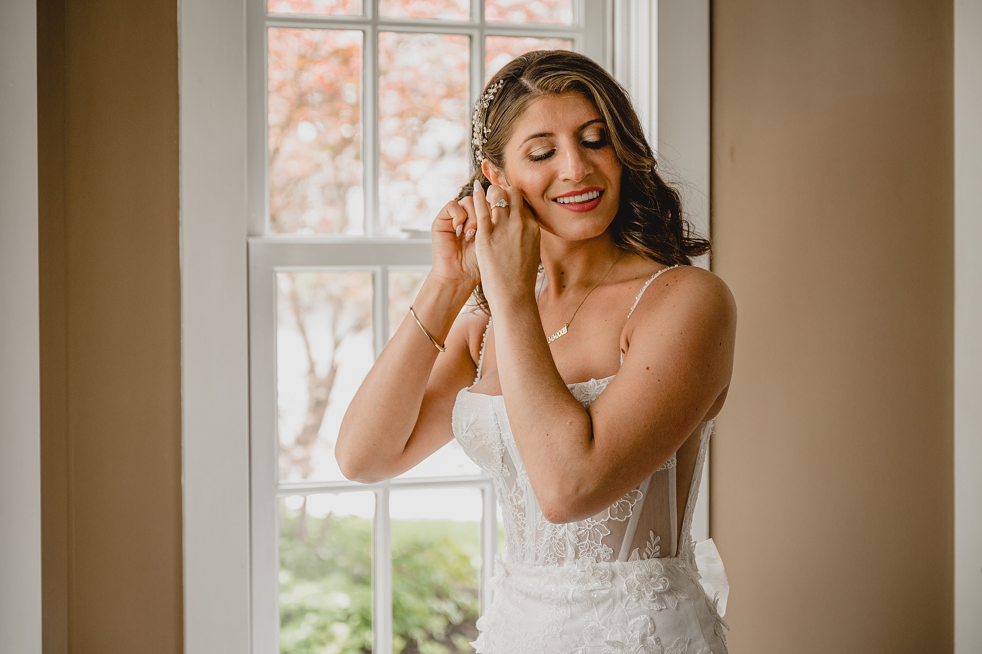 bride in wedding gown with corset top adjusts earrings