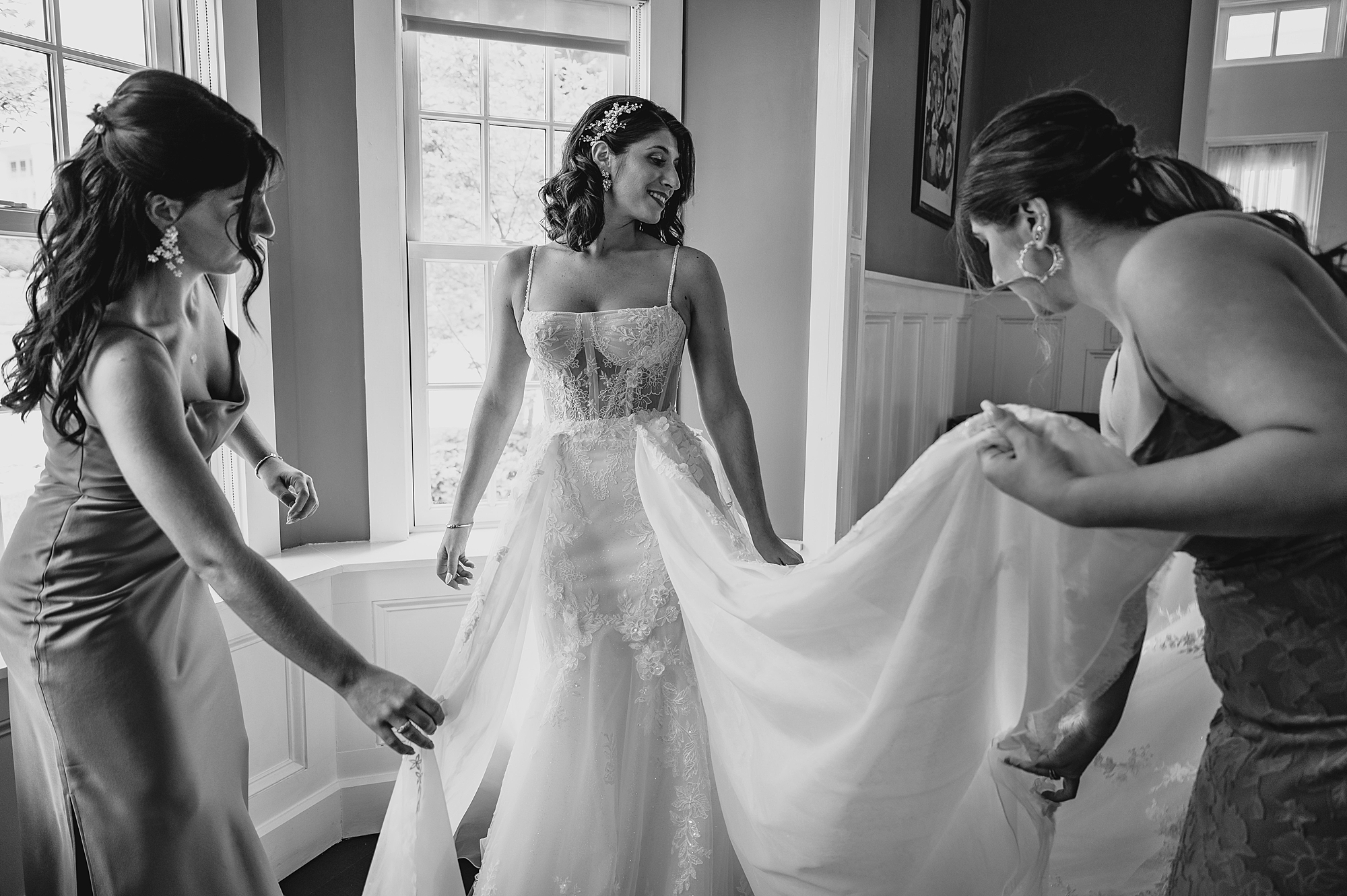 bridesmaids help hold out skirt of wedding gown for bride