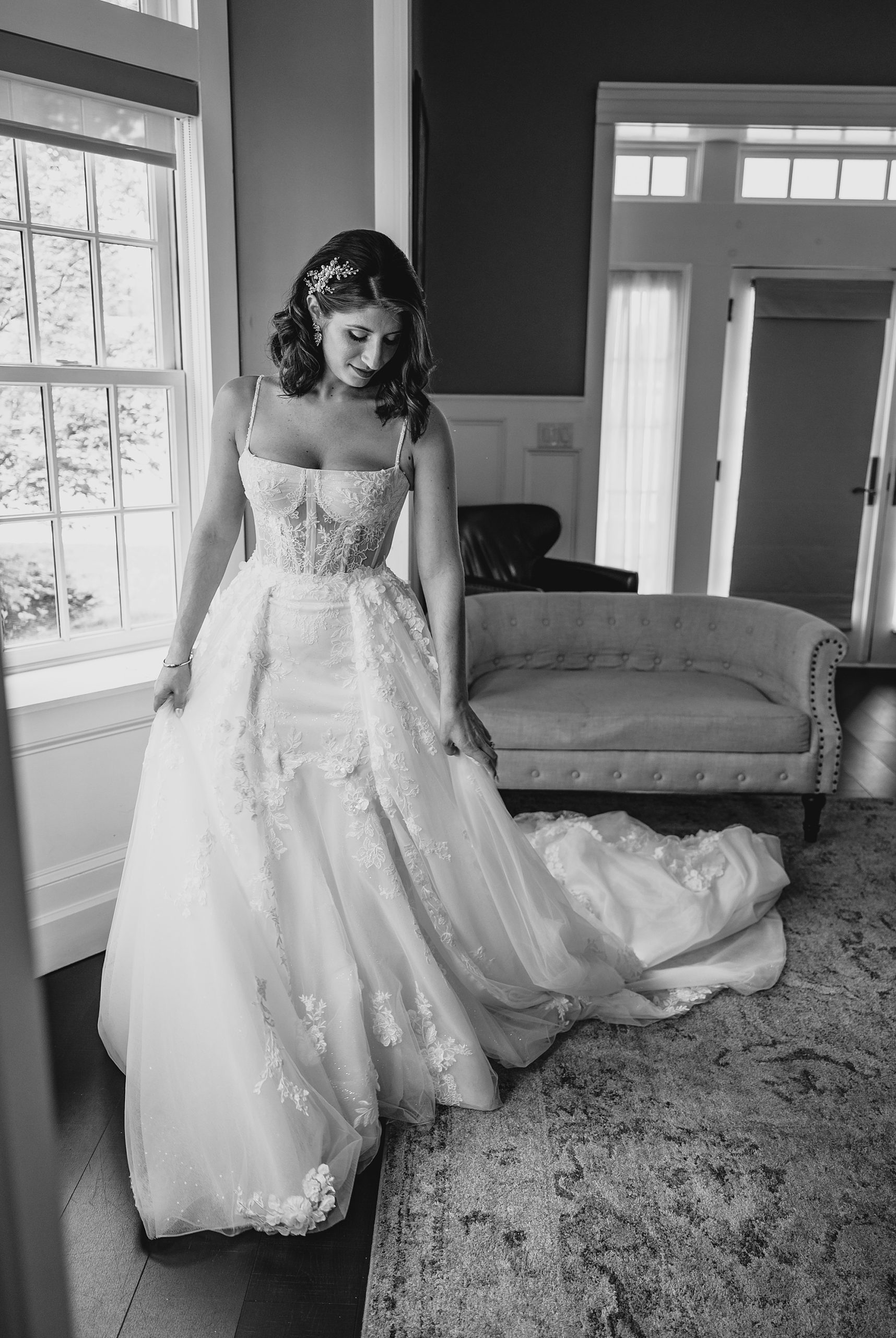 bride looks down at skirt of wedding dress in room at the Ryland Inn