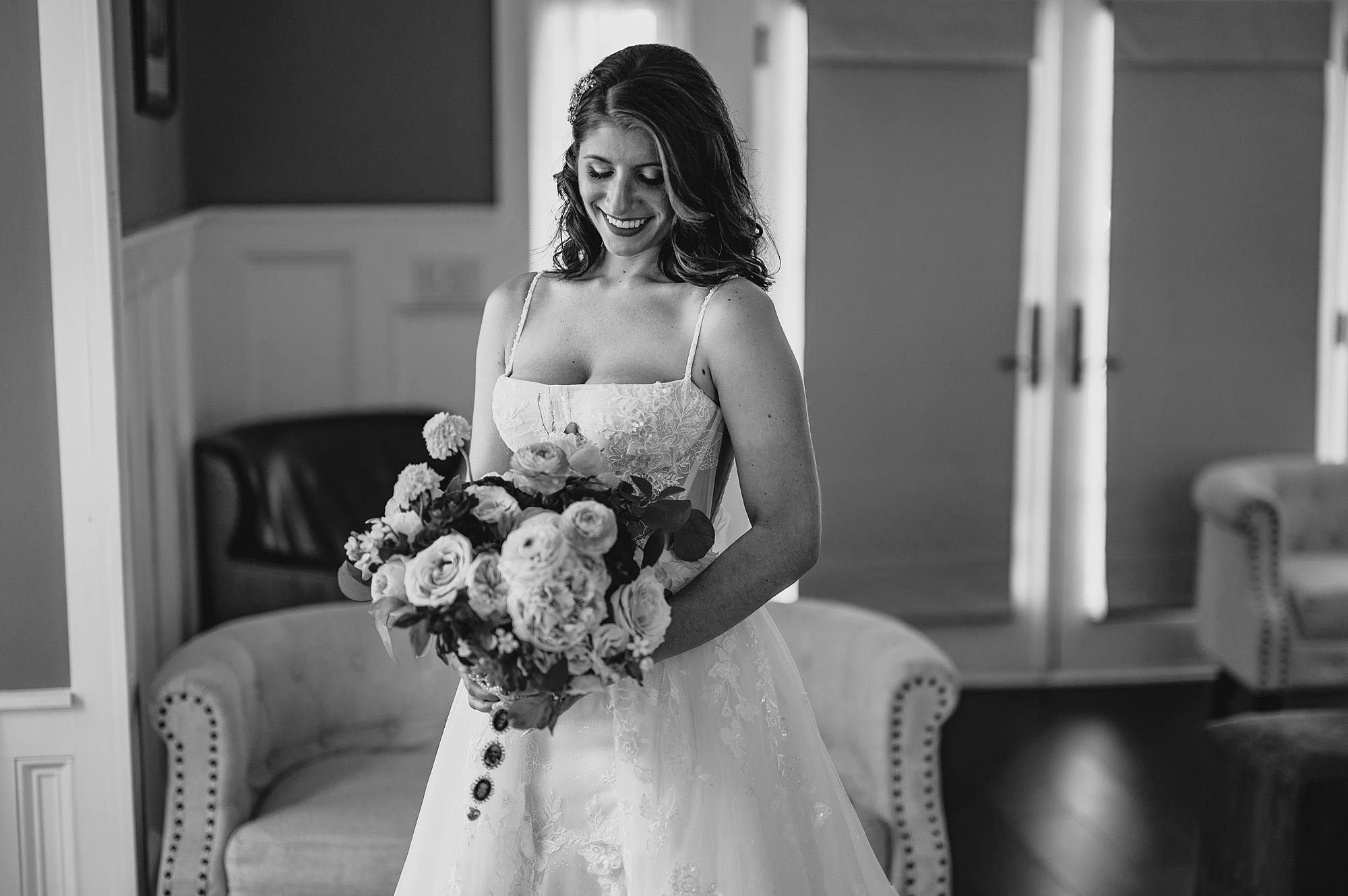 bride looks down at bouquet in hands smiling in suite