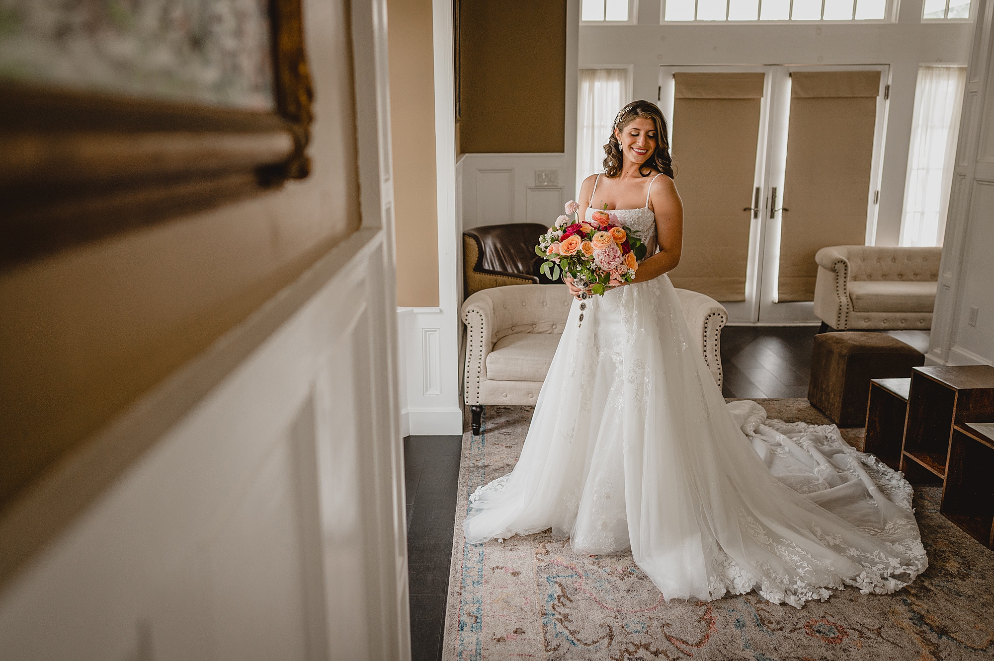 bride to be stands in wedding gown holding bouquet of pink flowers