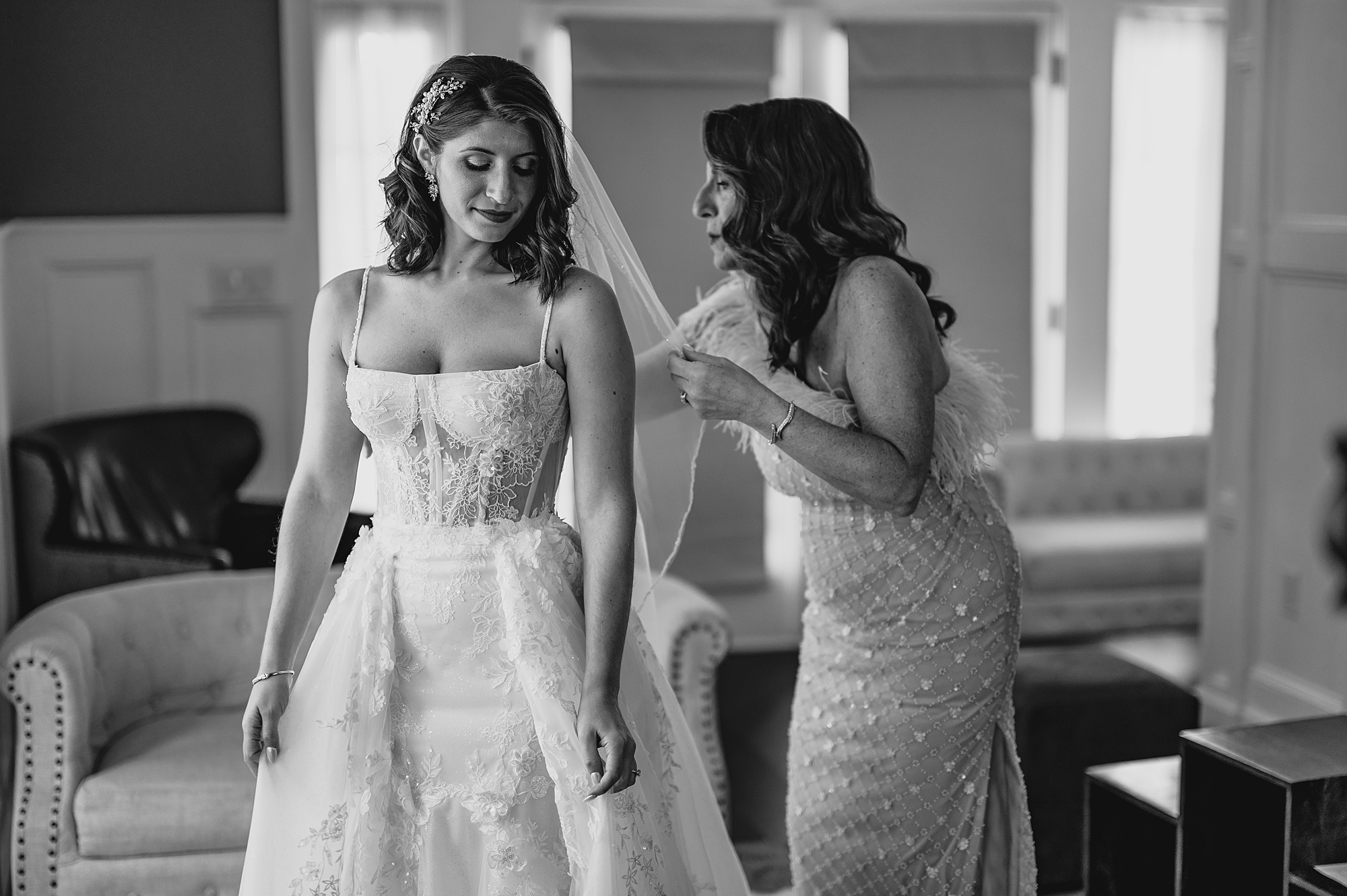 bridesmaid adjusts veil behind bride during prep