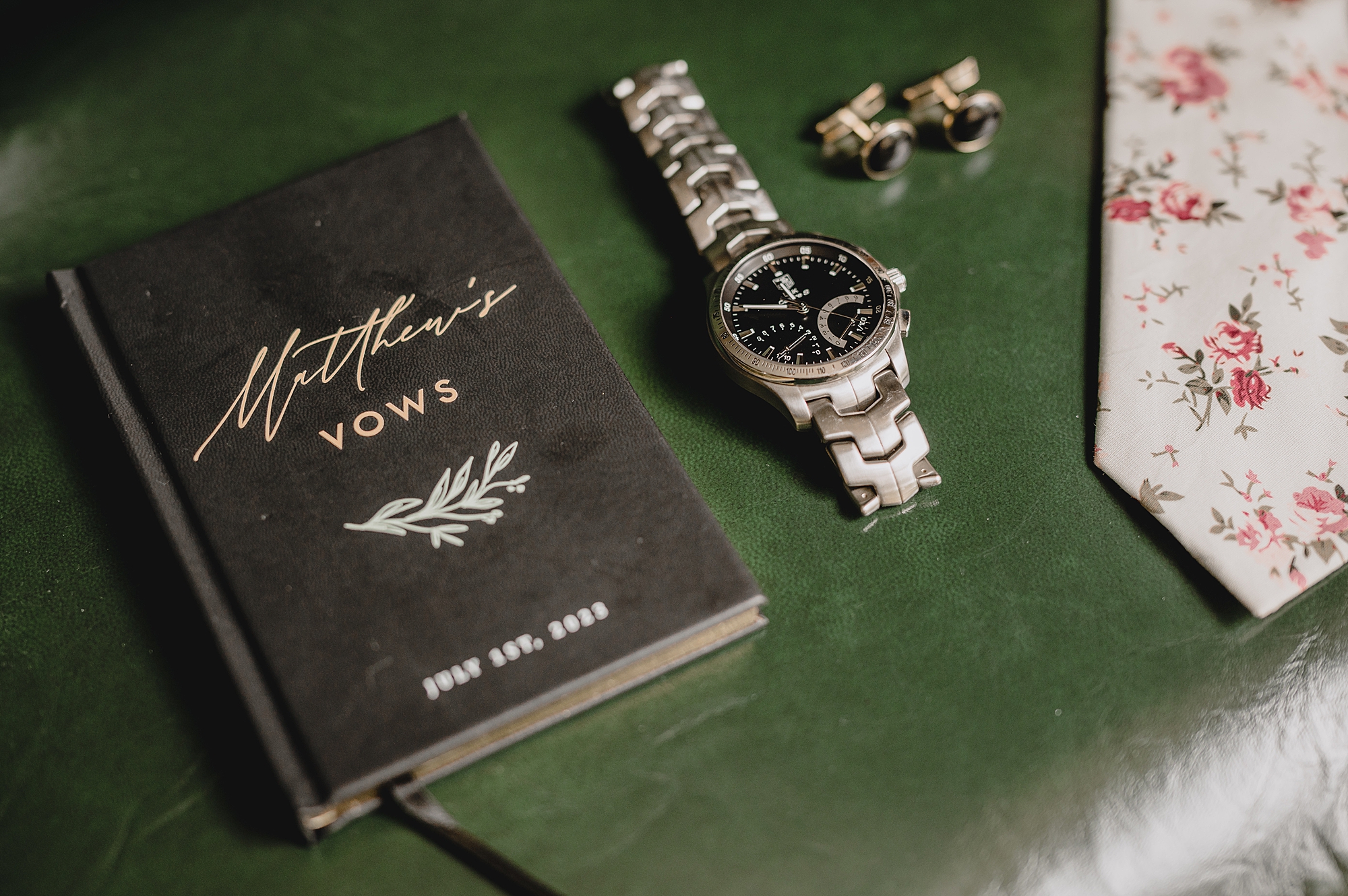 groom's vow booklet and watch on green mat