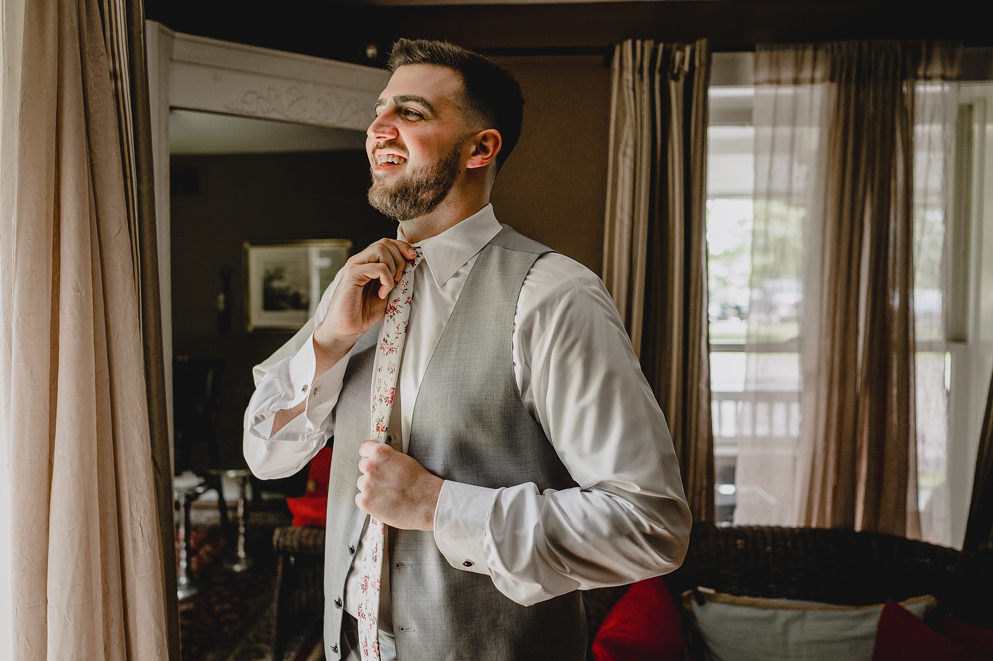groom in grey vest adjusts tie
