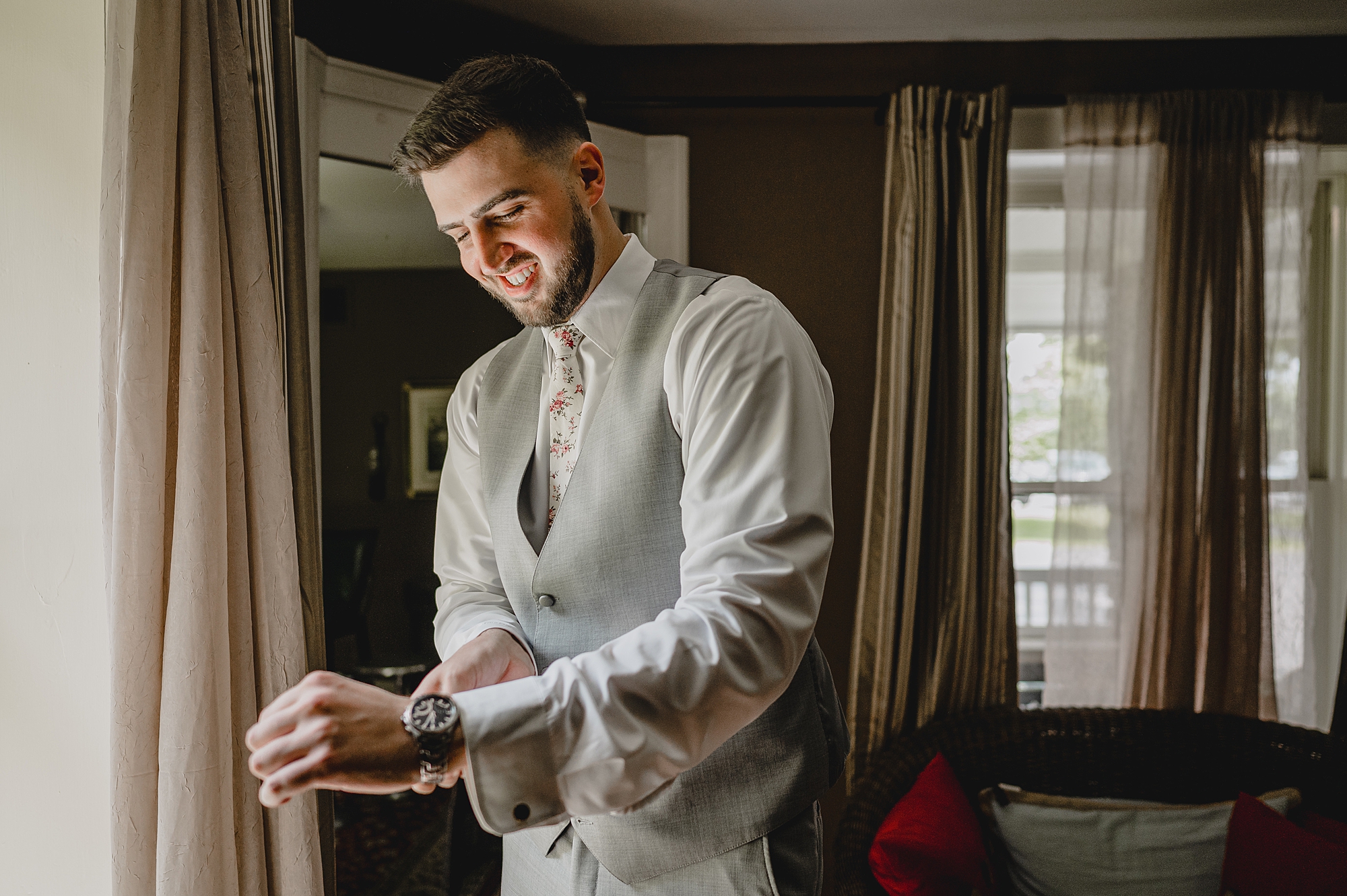 groom adjusts cufflinks in window of home