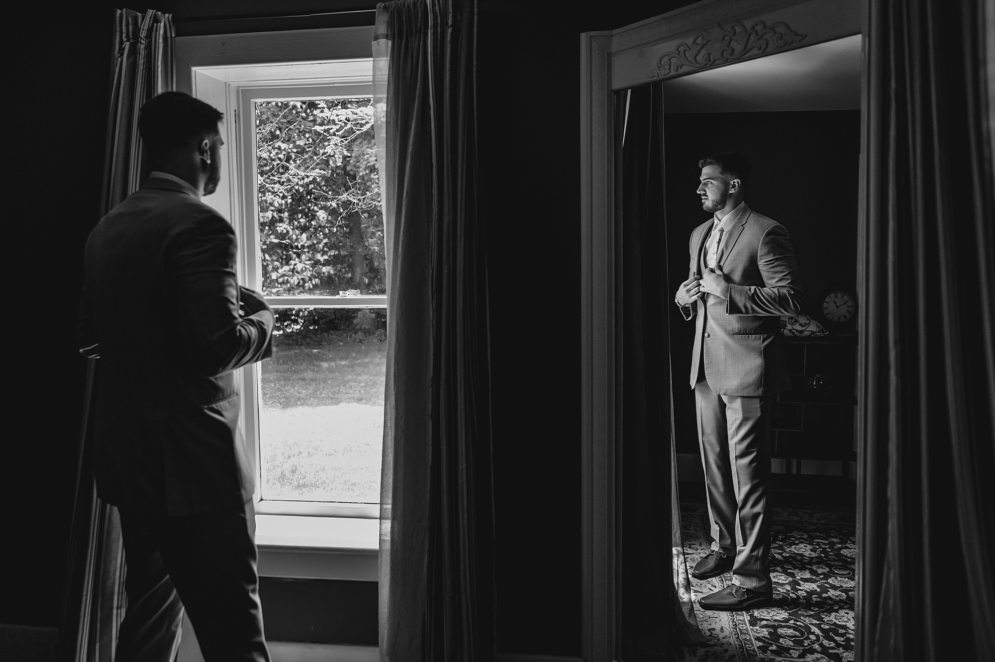 groom looks out the window adjusting his suit
