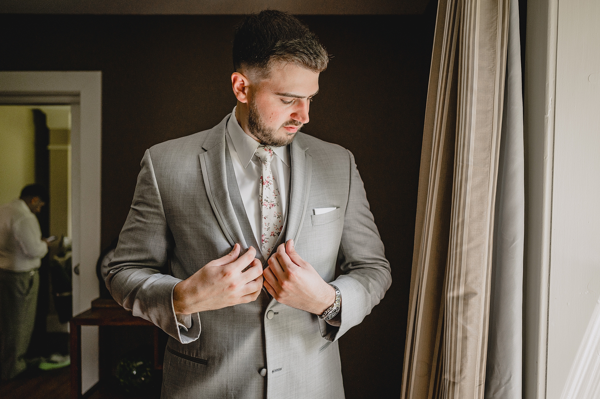 groom pulls suit jacket and adjusts buttons