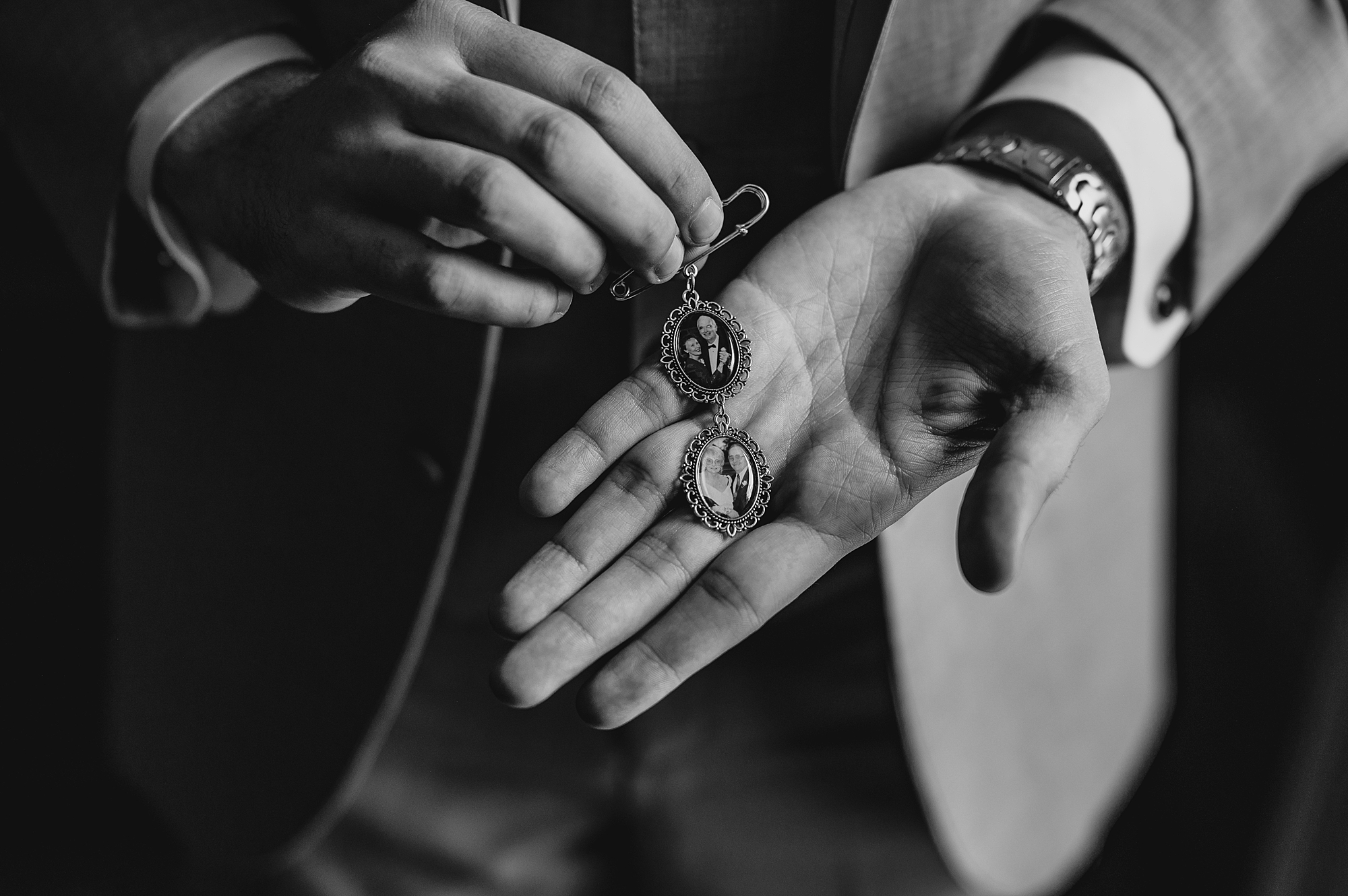 groom holds charms featuring photos of his grandparents against his palm