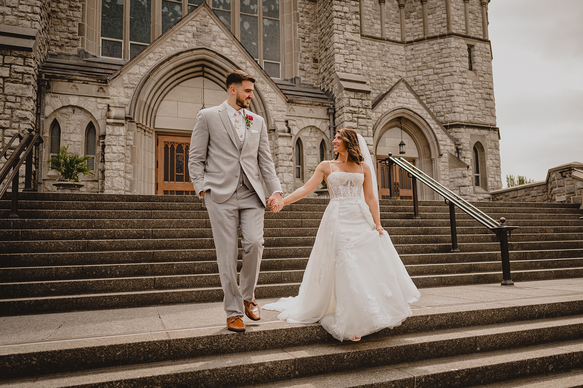 bride and groom hold hands walking down steps of church in New Jersey
