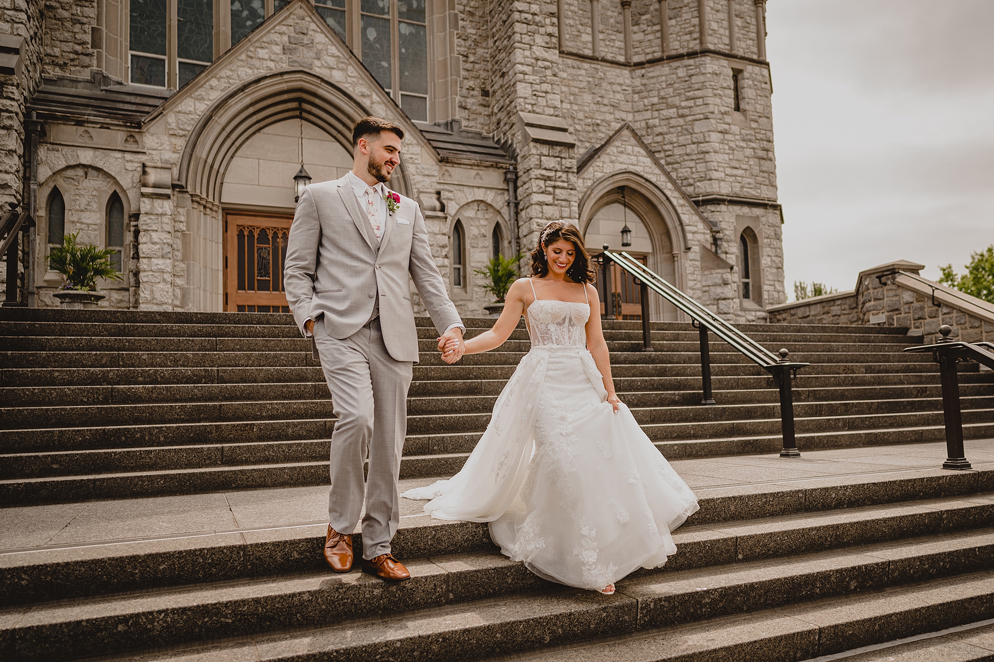 newlyweds hold hands on steps of New Jersey church