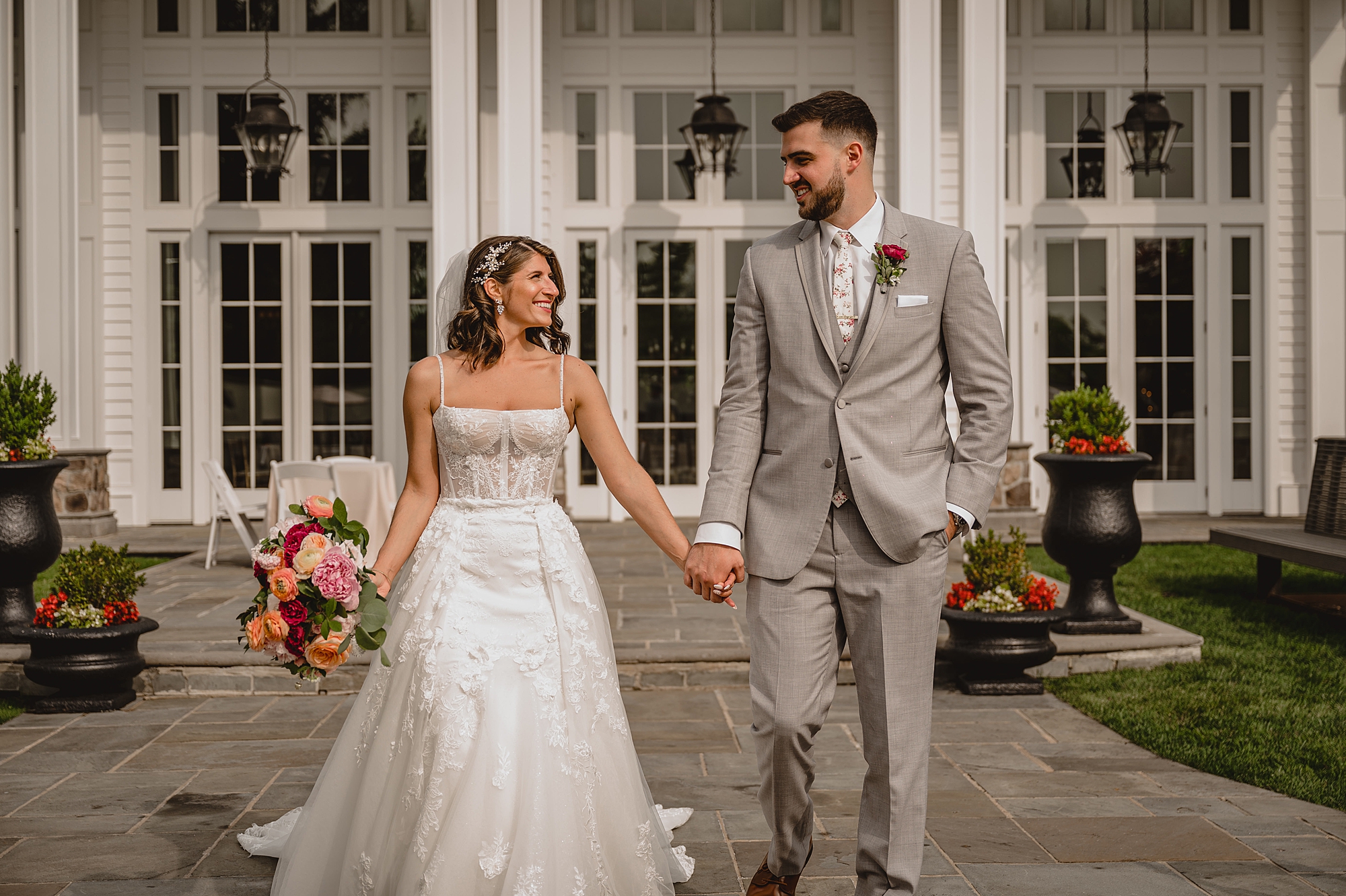 bride smiles up at groom walking in front of the Ryland Inn