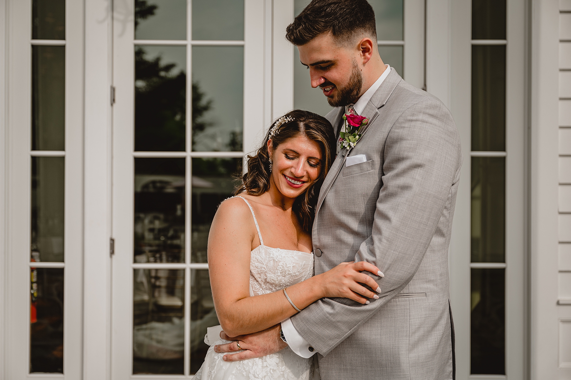 bride leans head against groom's chest standing outside the Ryland Inn