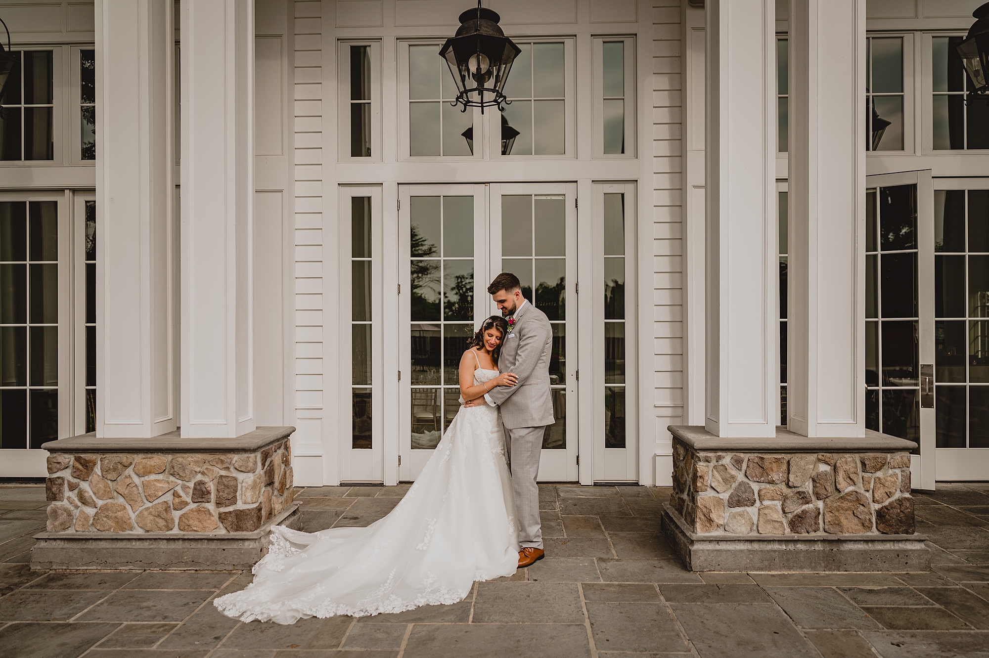 bride and groom pose between white columns of the Ryland Inn