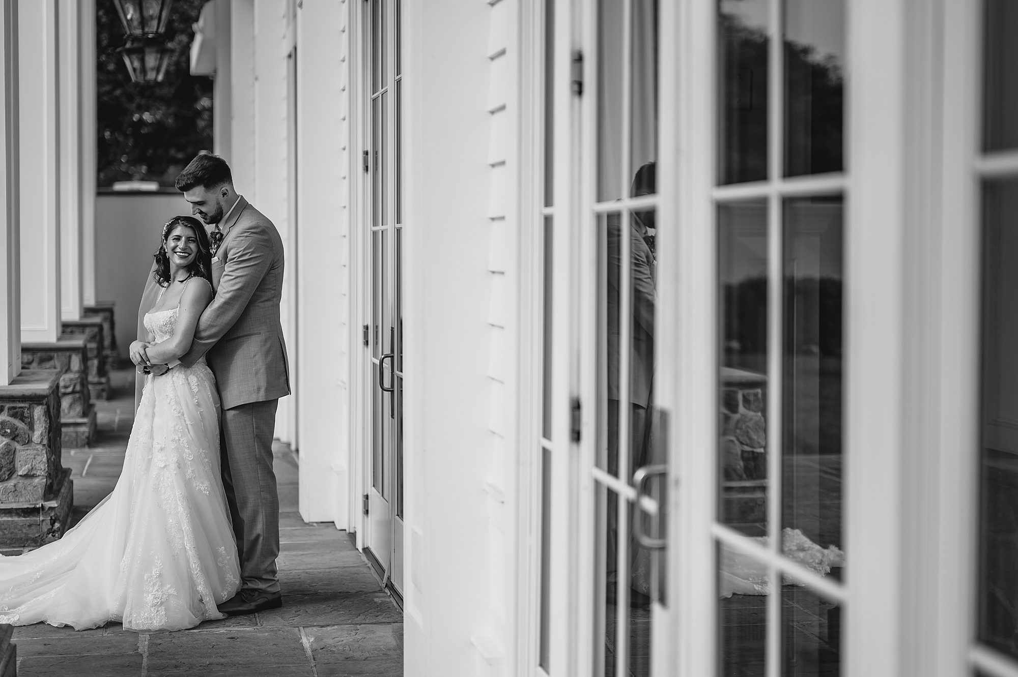 newlyweds hug by glass paned doors at the Ryland Inn
