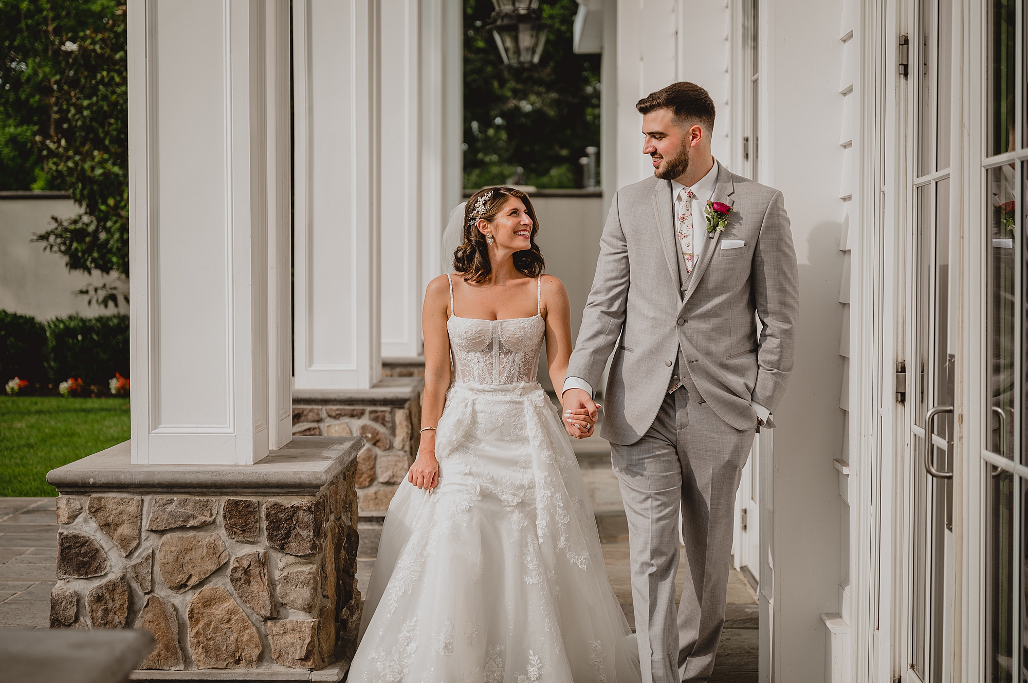 bride and groom hold hands walking under patio at the Ryland Inn