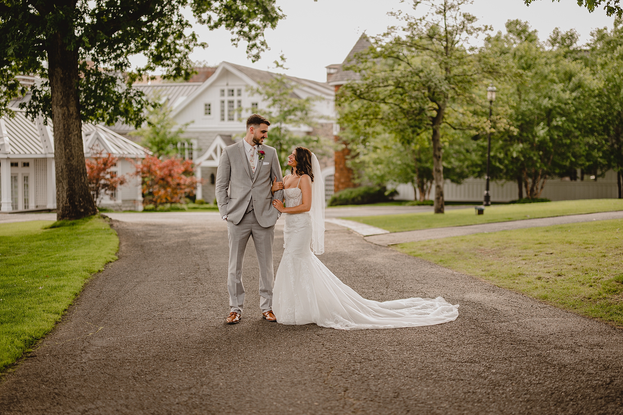 bride holds groom's arm looking up at him outside the Ryland Inn