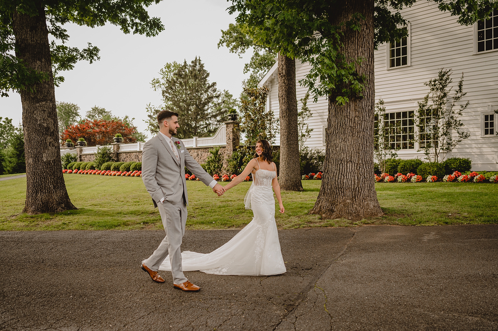 bride walks ahead of groom on driveway of the Ryland Inn