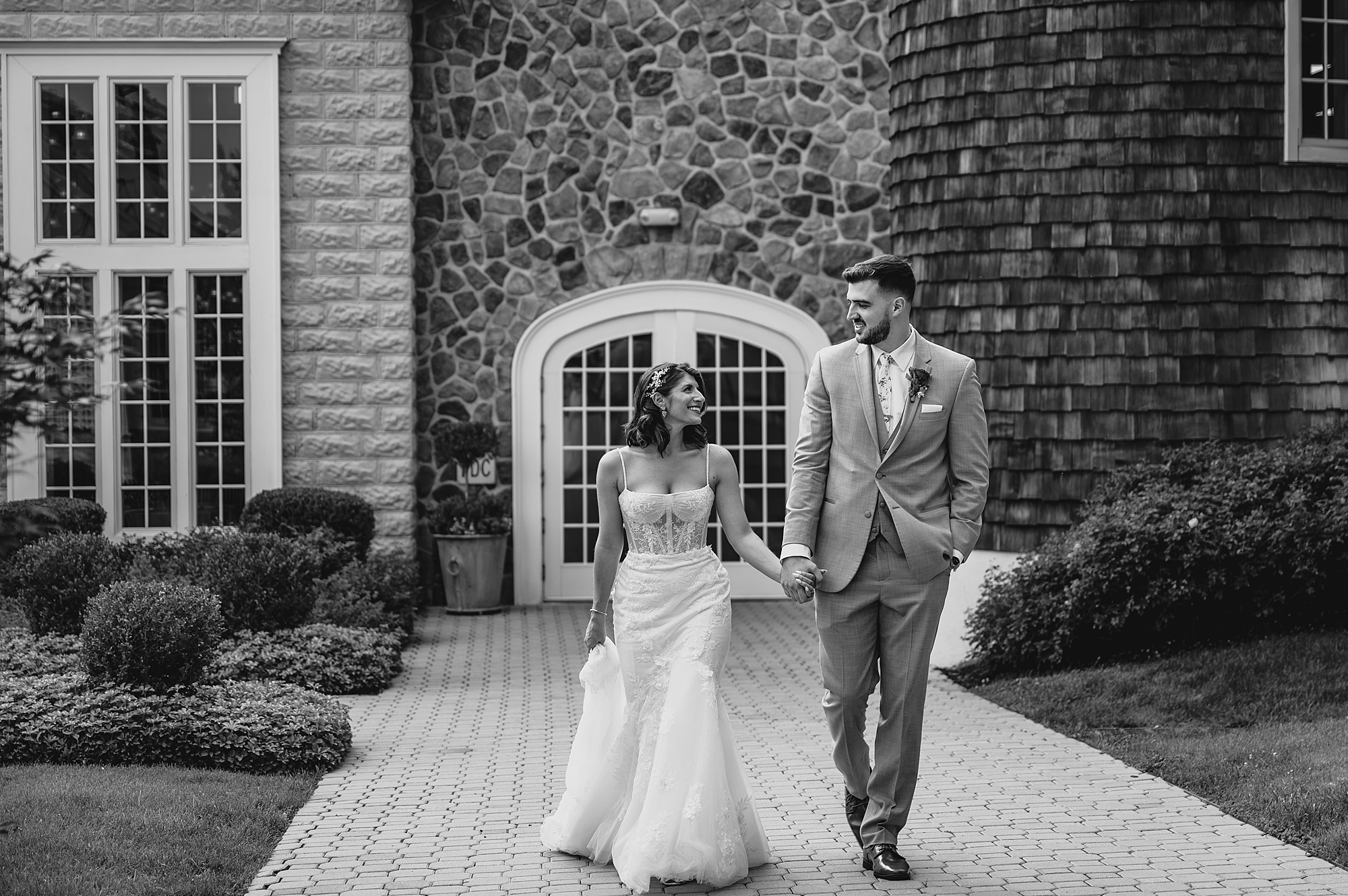 newlyweds hold hands walking away from the tower at the Ryland Inn