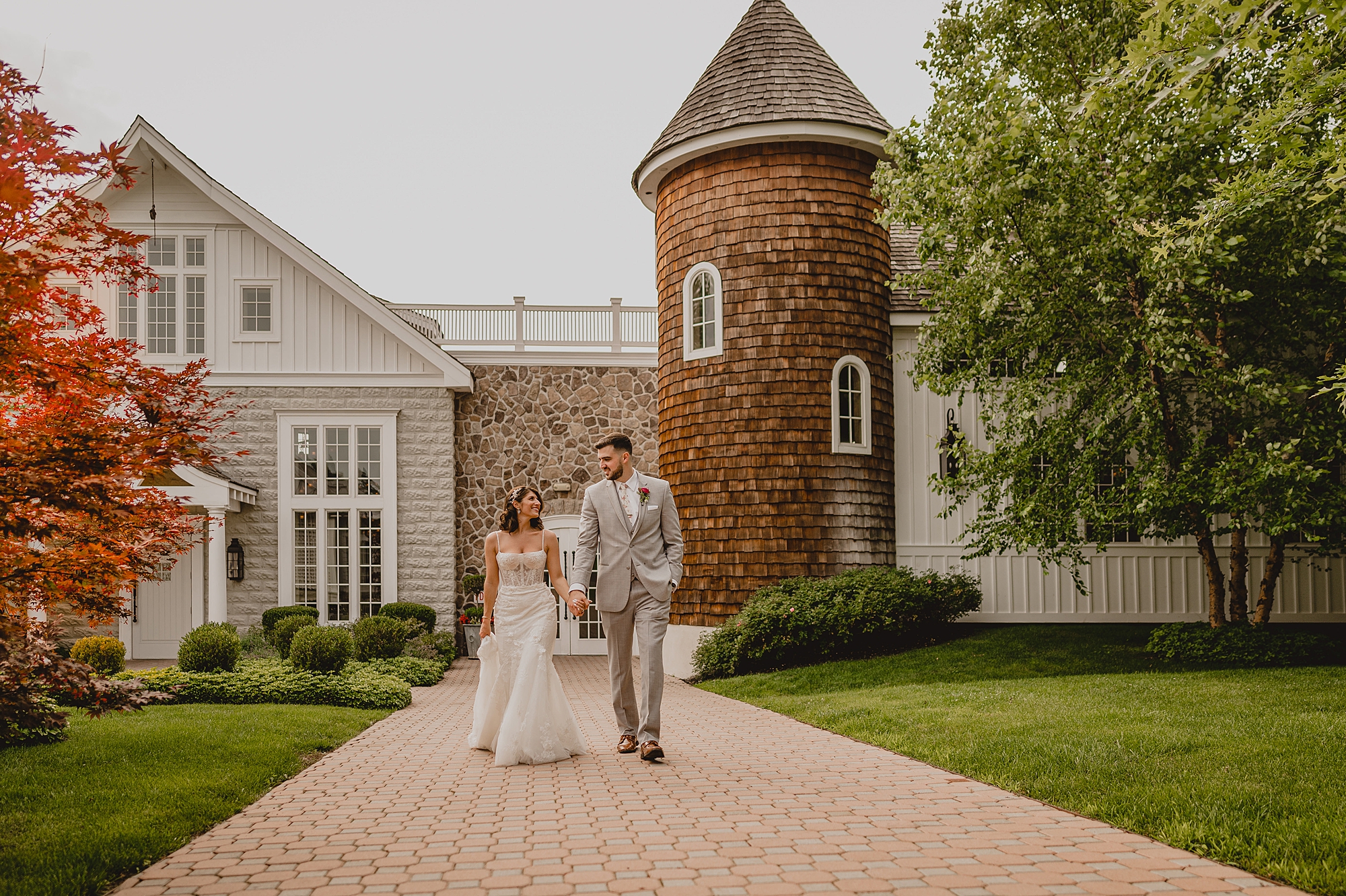 bride and groom walk holding hands away from turret tower at the Ryland Inn