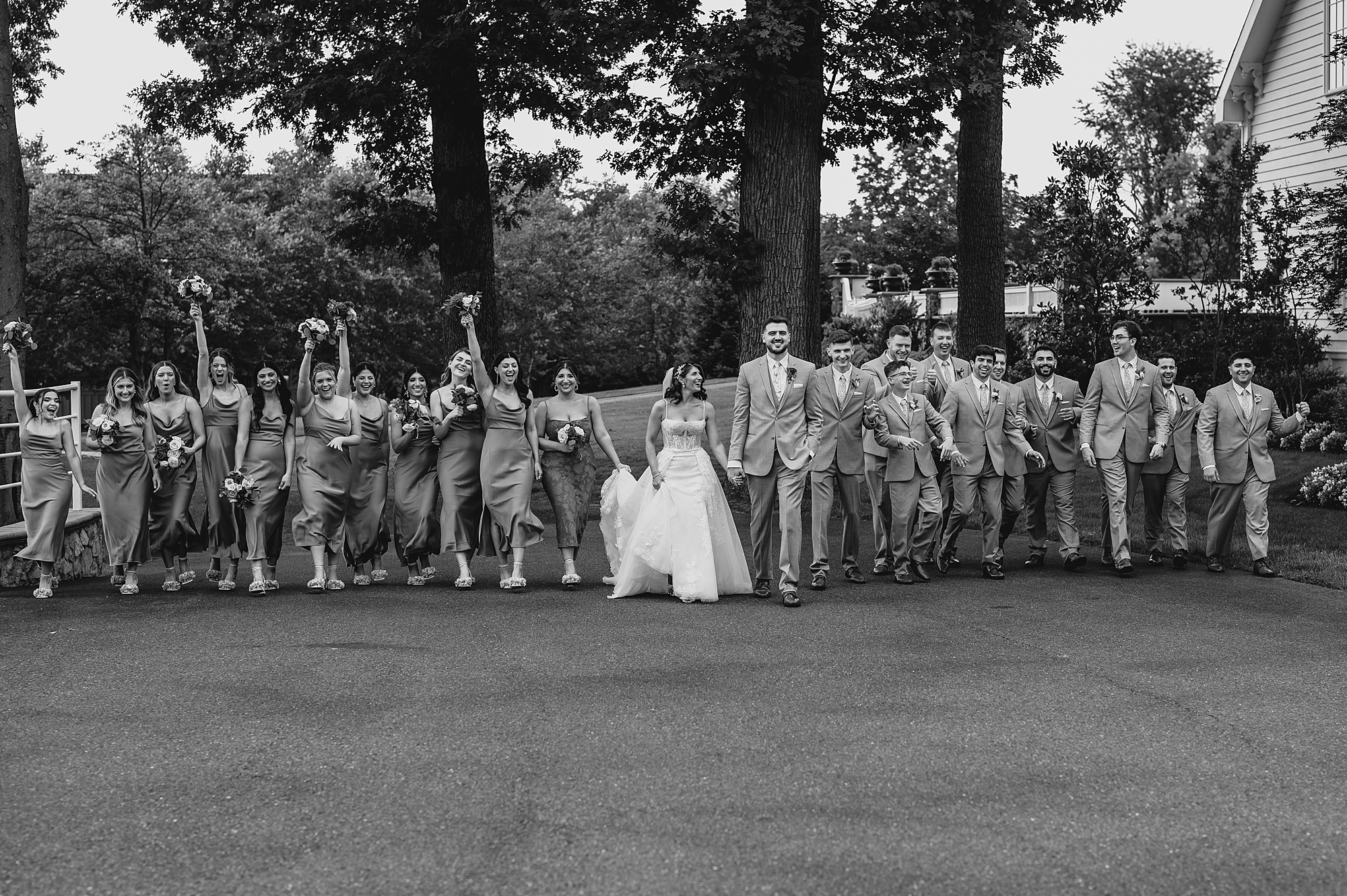 newlyweds walk with wedding party across lot at the Ryland Inn