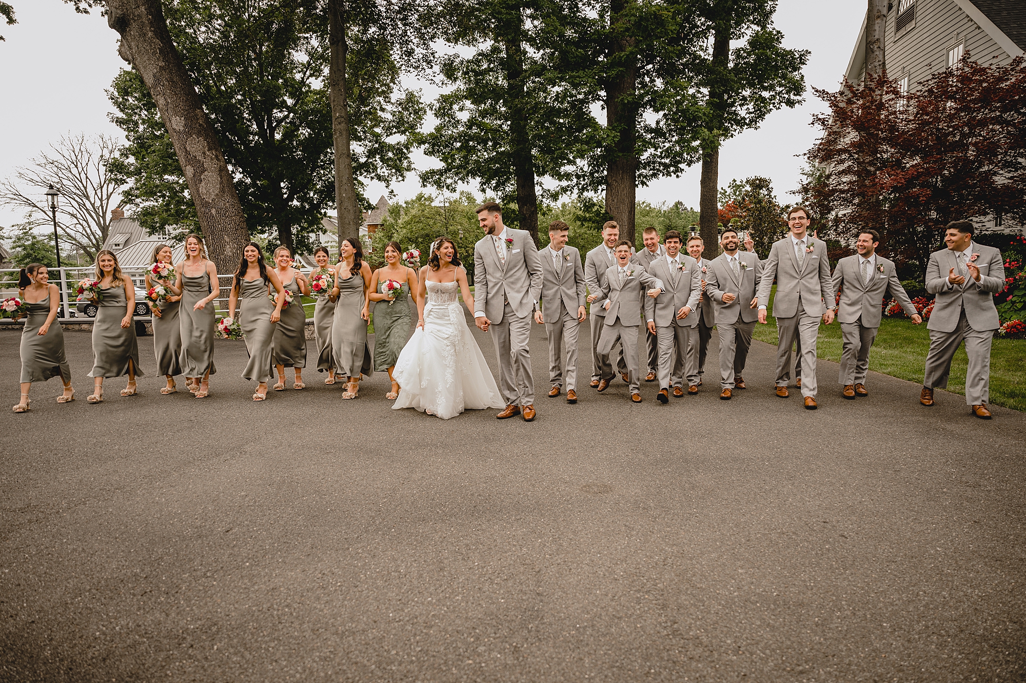 bride and groom hold hands walking with wedding party