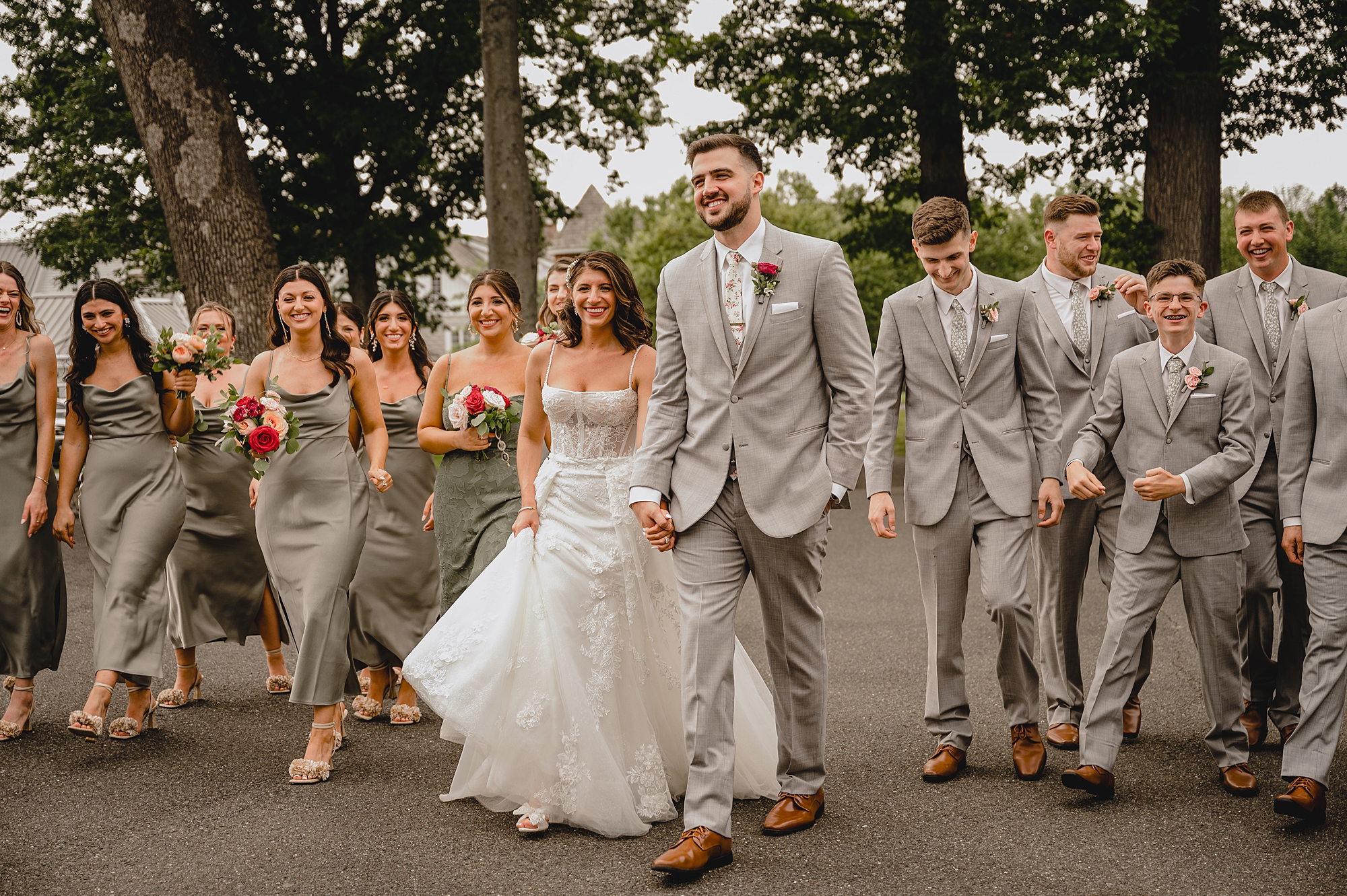 newlyweds smile holding hands walking with bridesmaids and groomsmen at the Ryland Inn