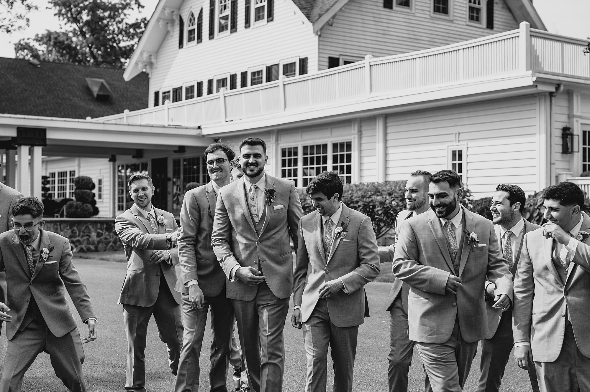 groom laughs with groomsmen outside the Ryland Inn