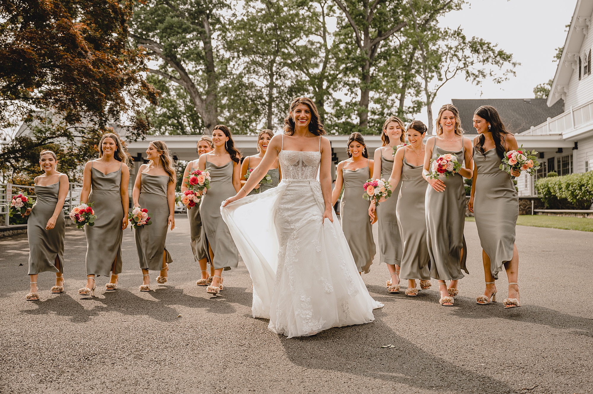 bride smiles walking with bridesmaids behind her in green gowns
