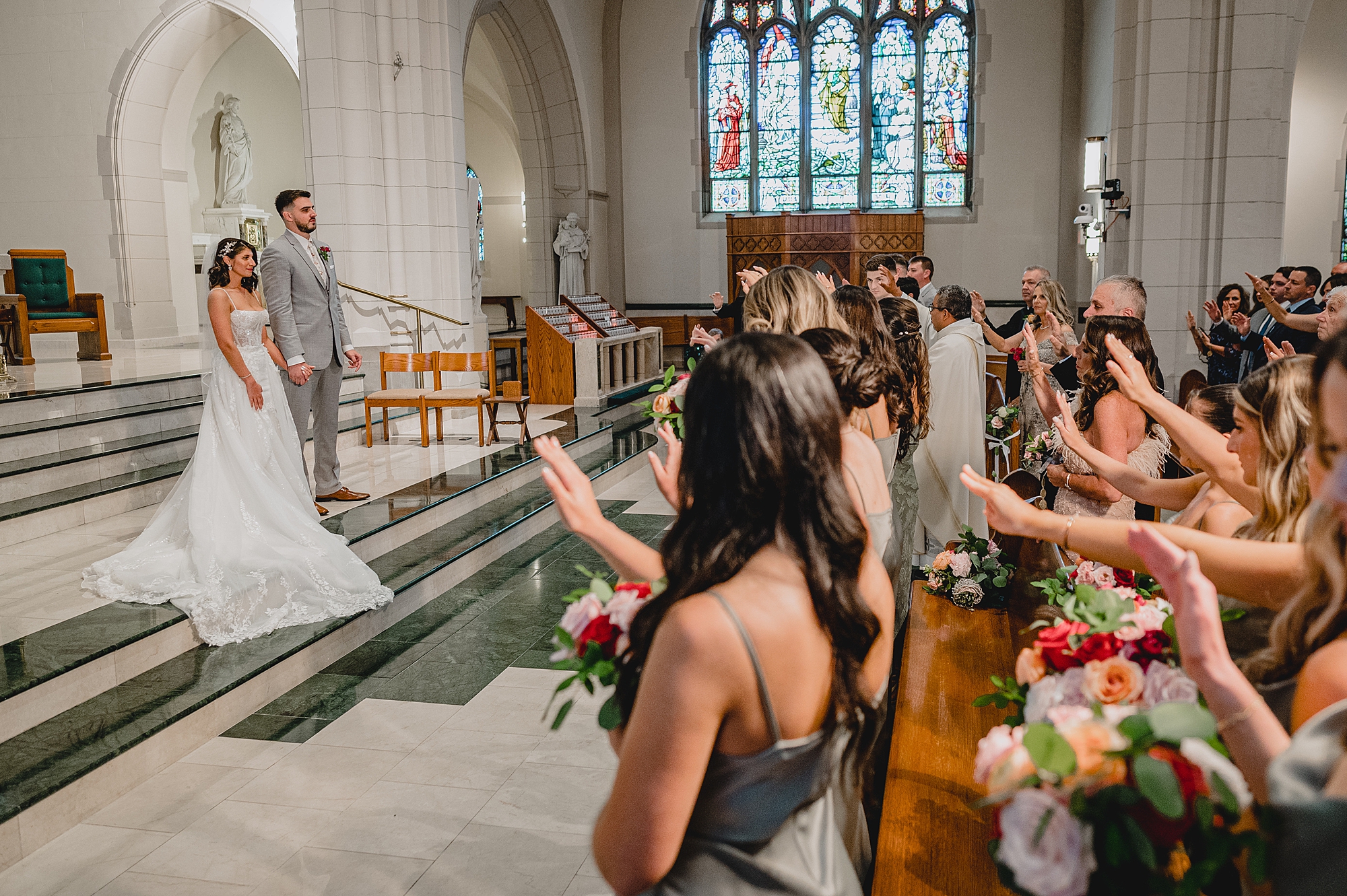 bridesmaids and family pray over bride and groom during traditional church ceremony in New Jersey