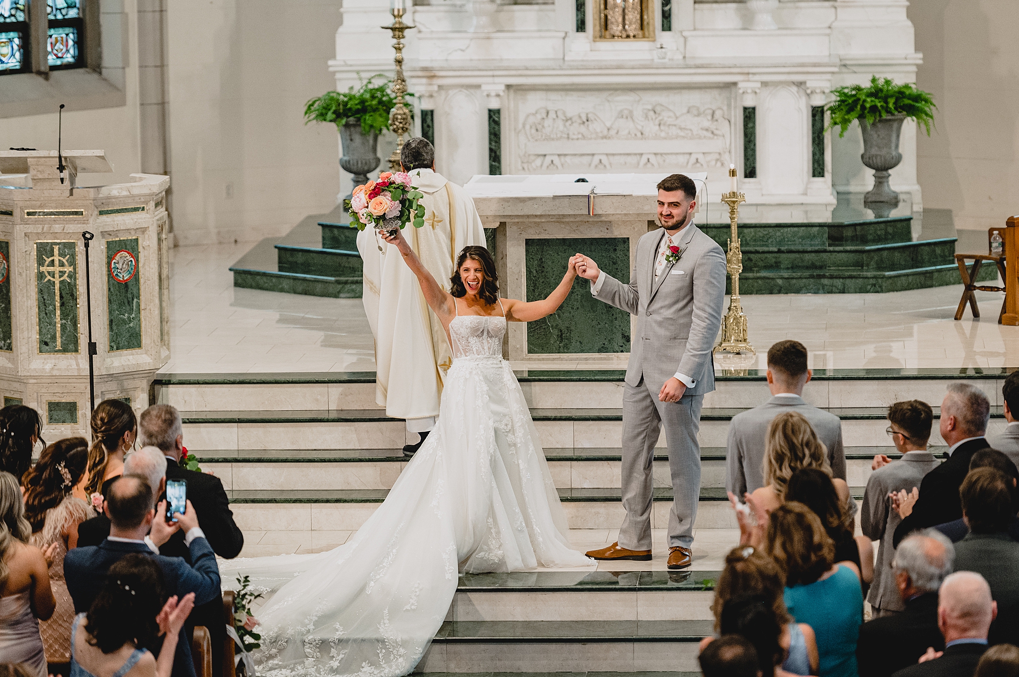 bride cheers holding groom's hand during traditional church ceremony in New Jersey