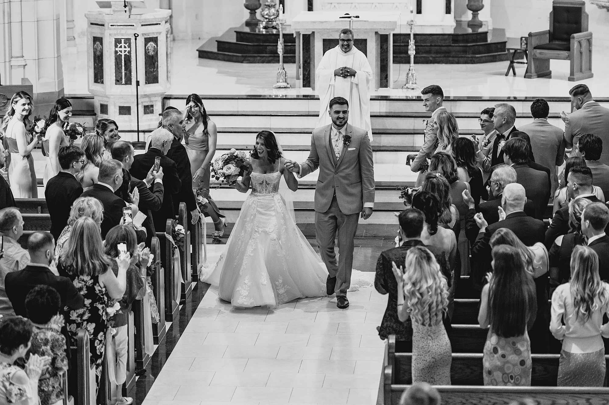 newlyweds hold hands walking up aisle after traditional church ceremony in New Jersey