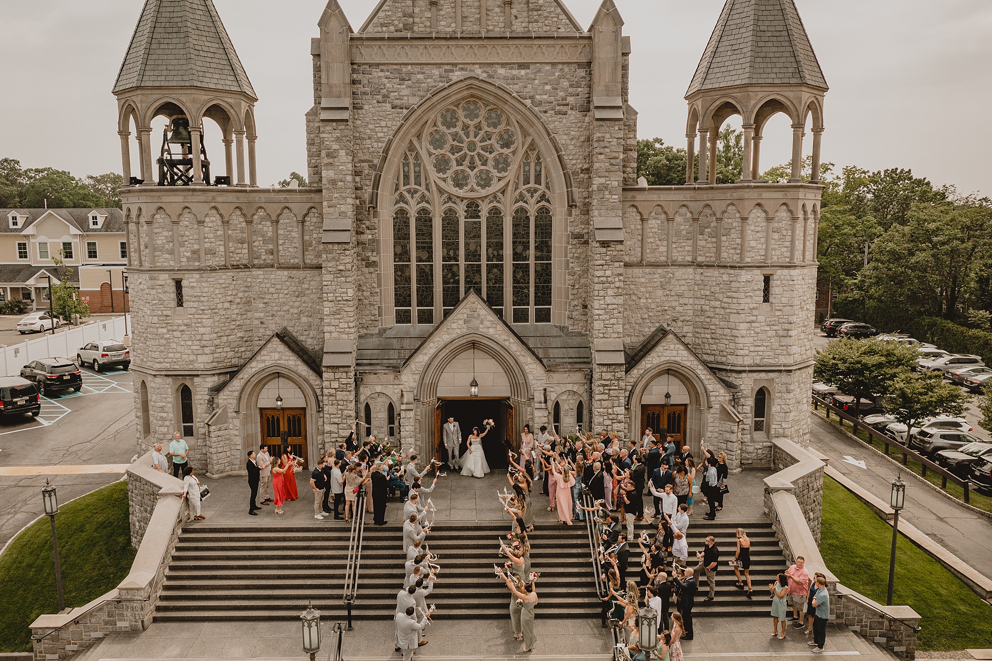 wedding guests wait on steps for bride and groom after traditional church ceremony in New Jersey