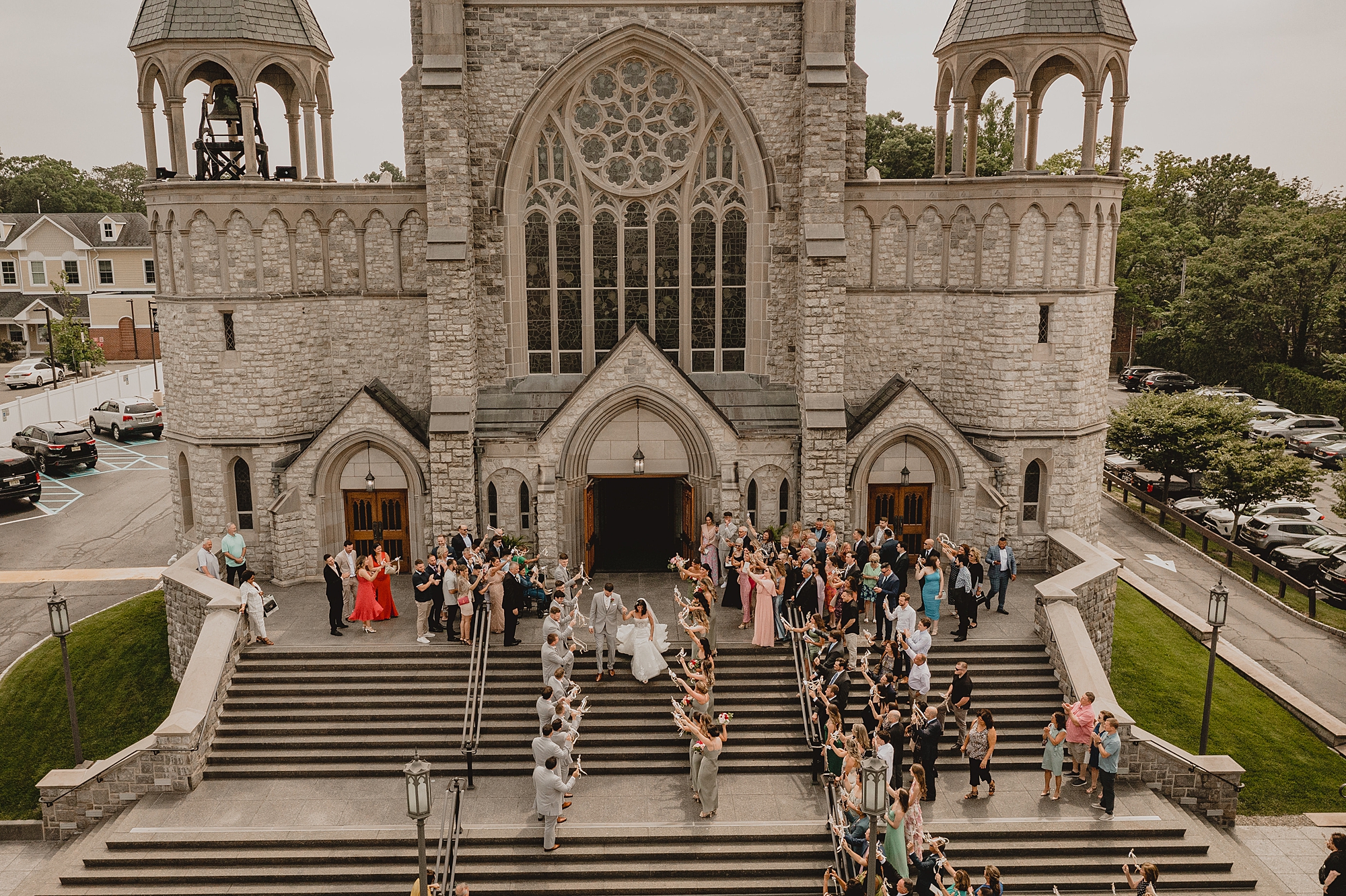 guests mingle on steps as bride and groom exit church from traditional church ceremony in New Jersey