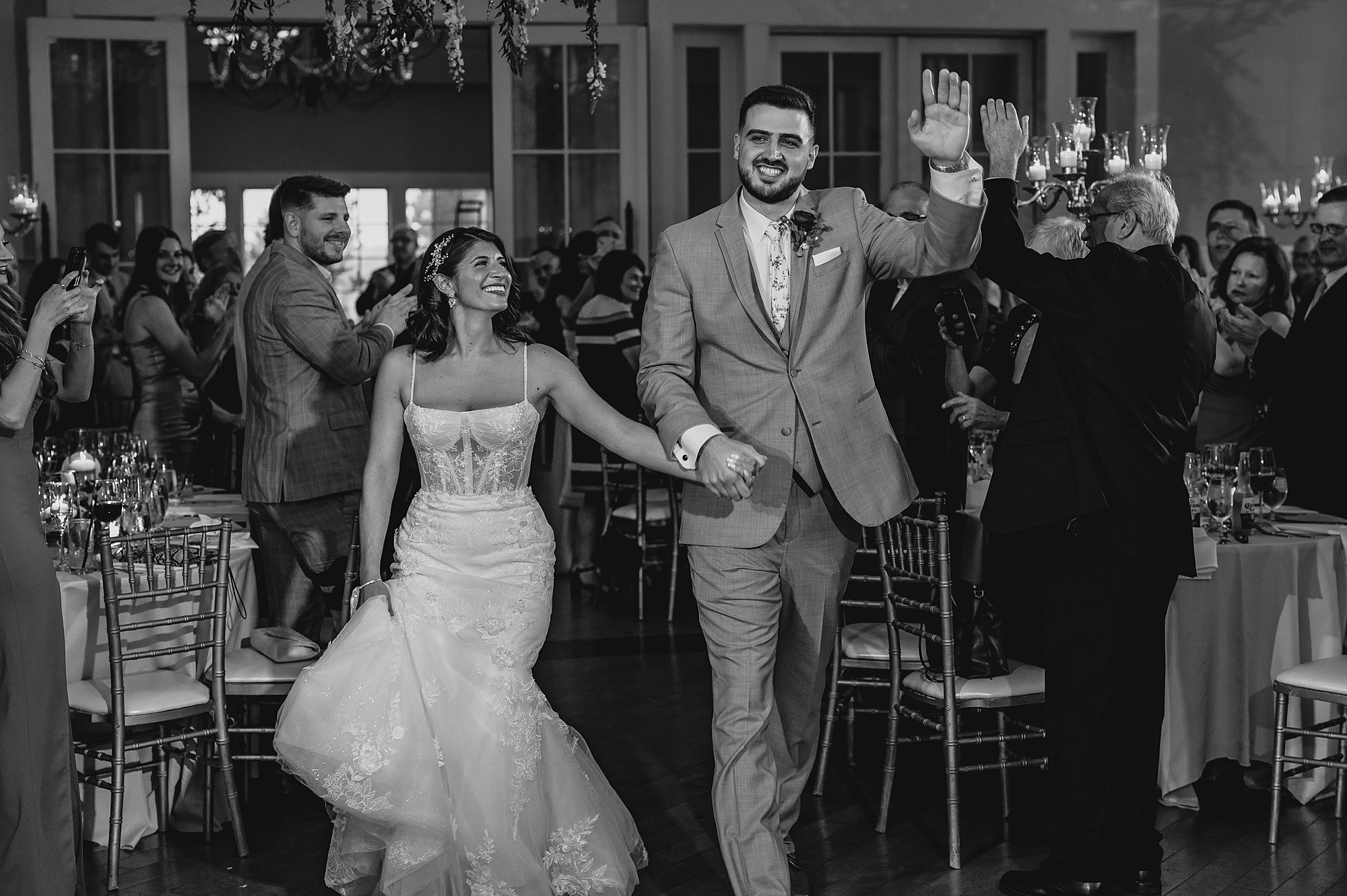 newlyweds enter reception laughing and waving at guests