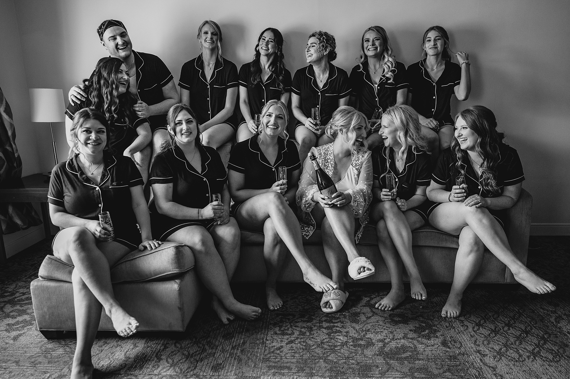 bride sits with wedding party in matching pajamas before wedding day