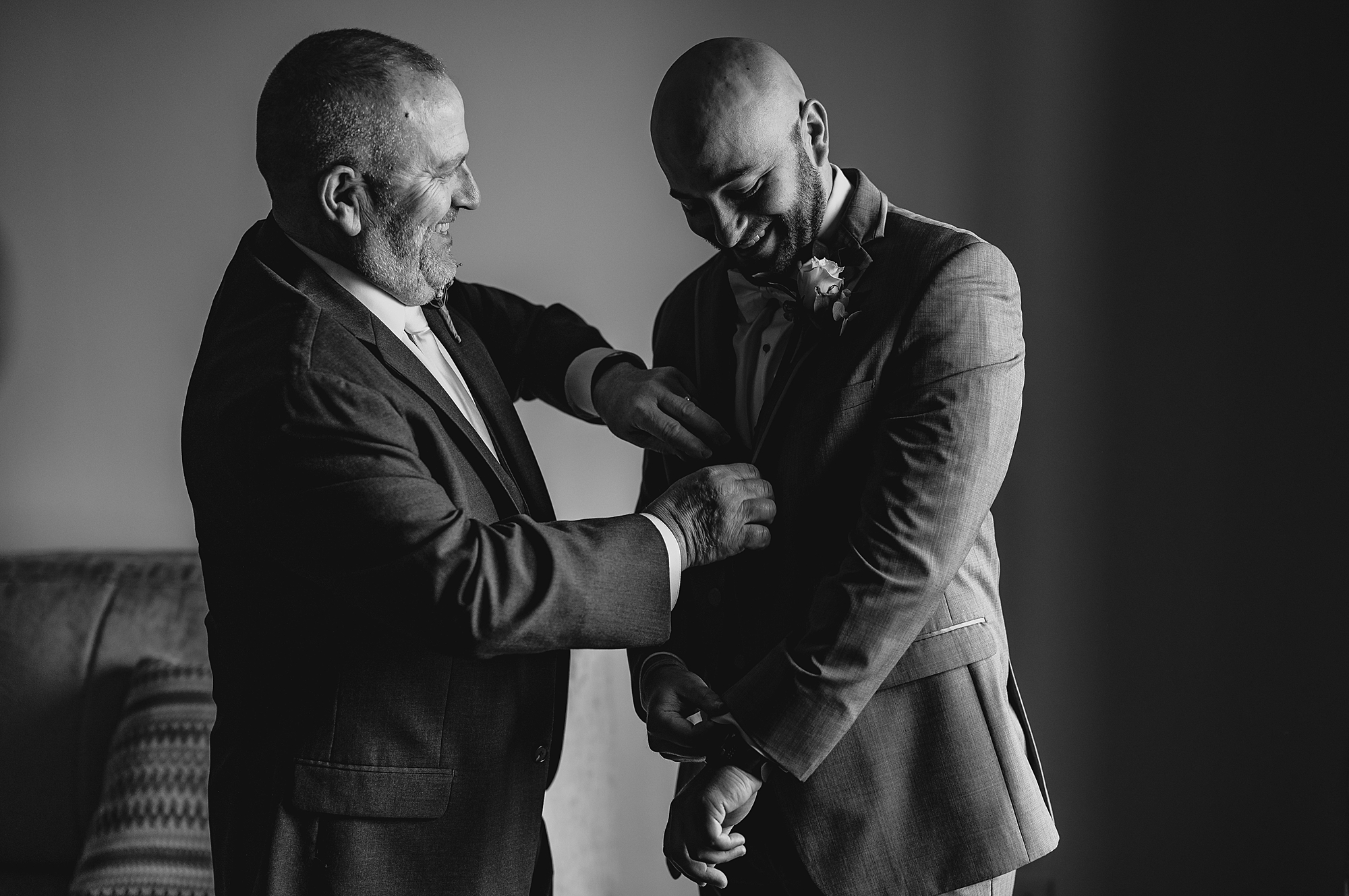 father helps groom with jacket before wedding day