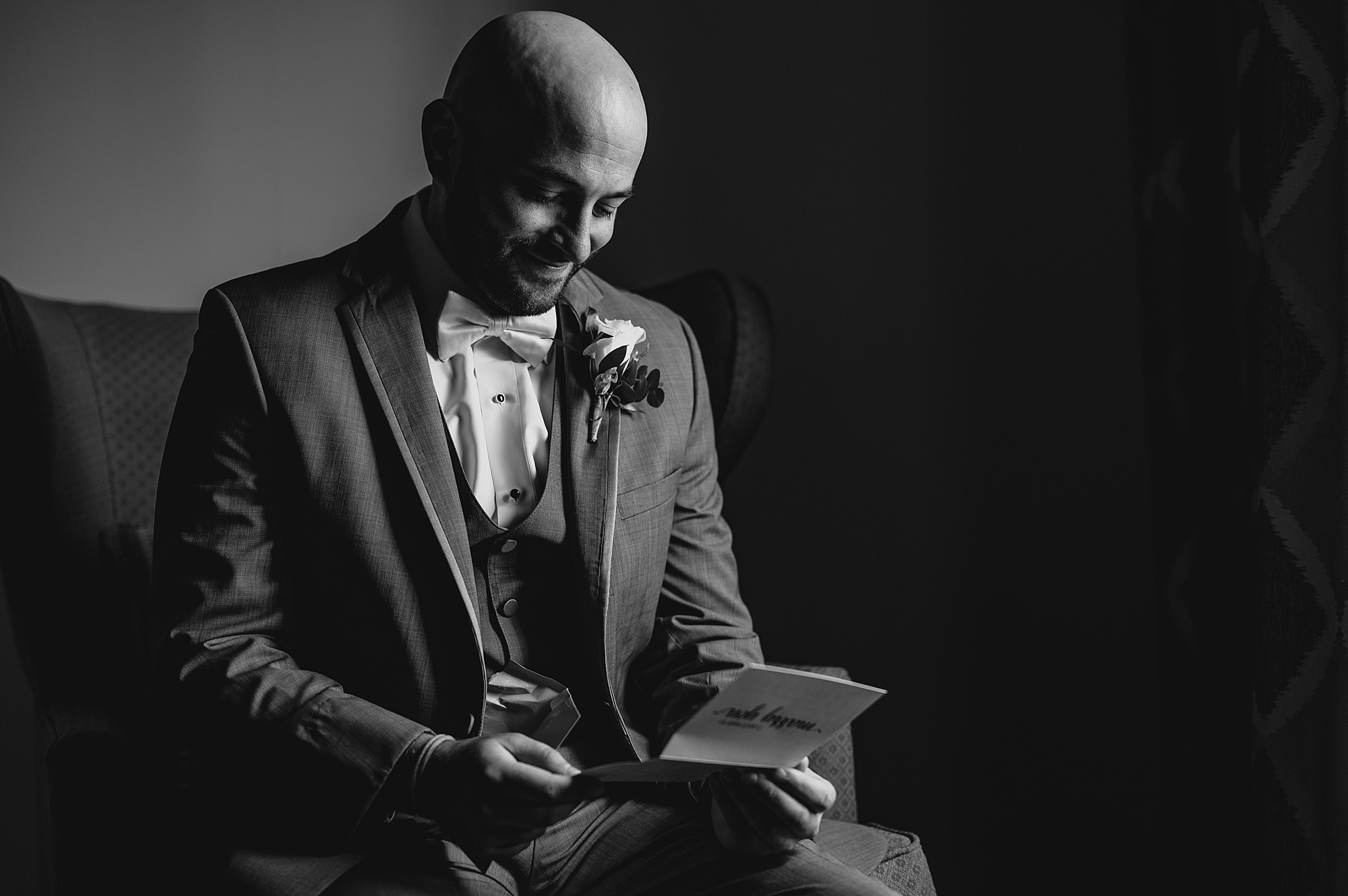groom smiles reading card on wedding morning