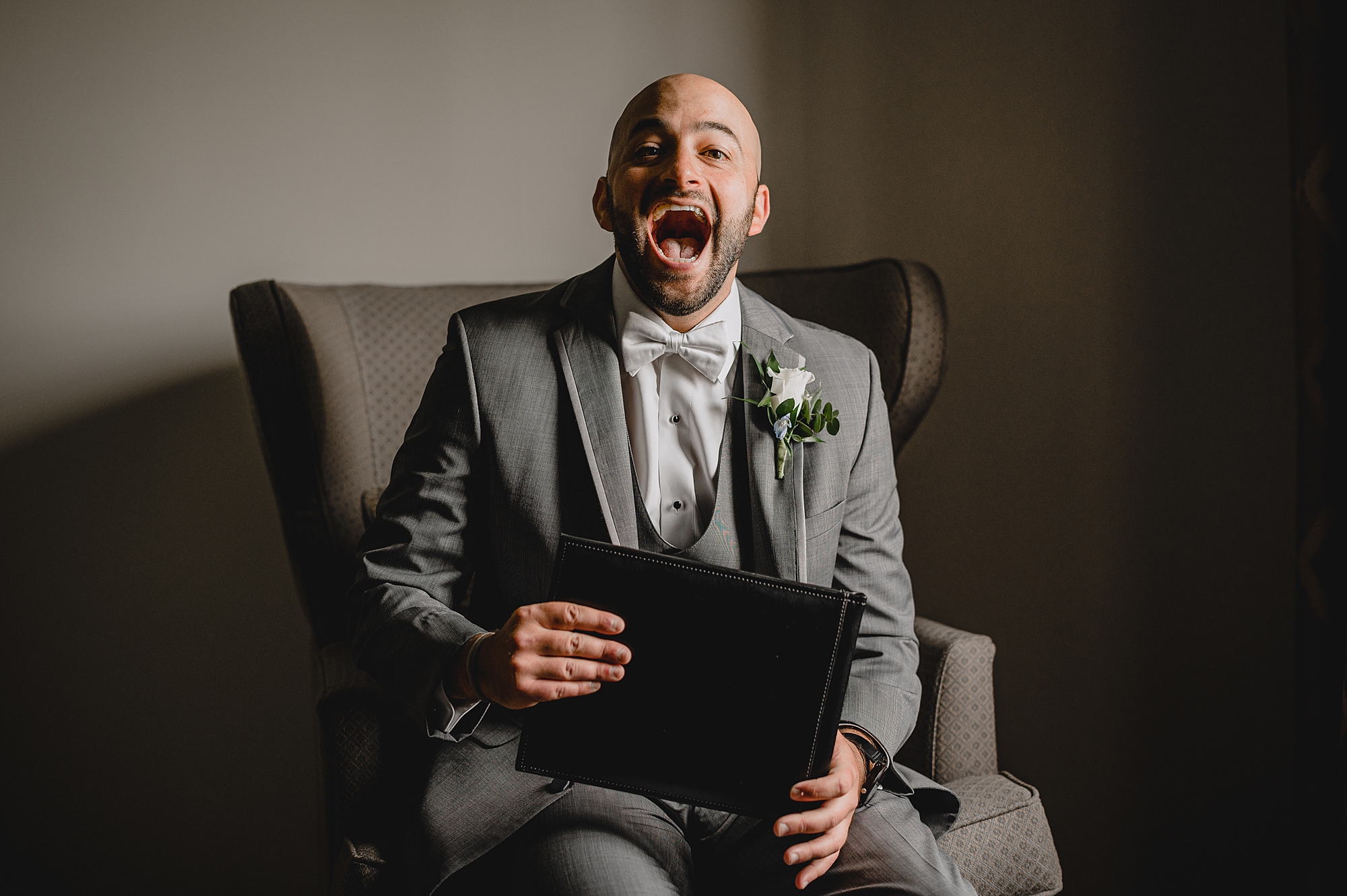 groom laughs and smiles during present opening