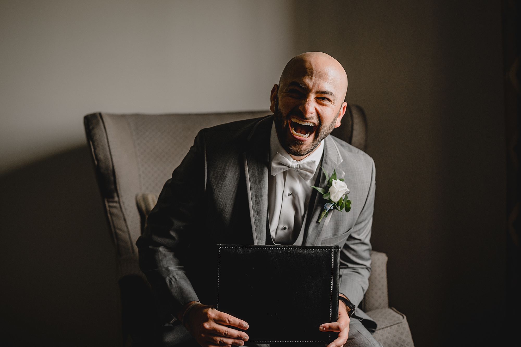 groom grins looking down at photo album in his hands