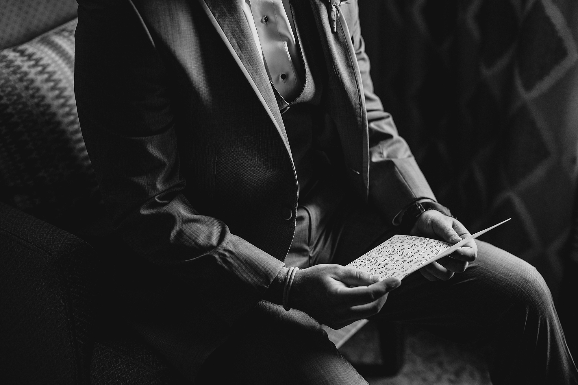 groom reads handwritten letter with gift on morning of wedding