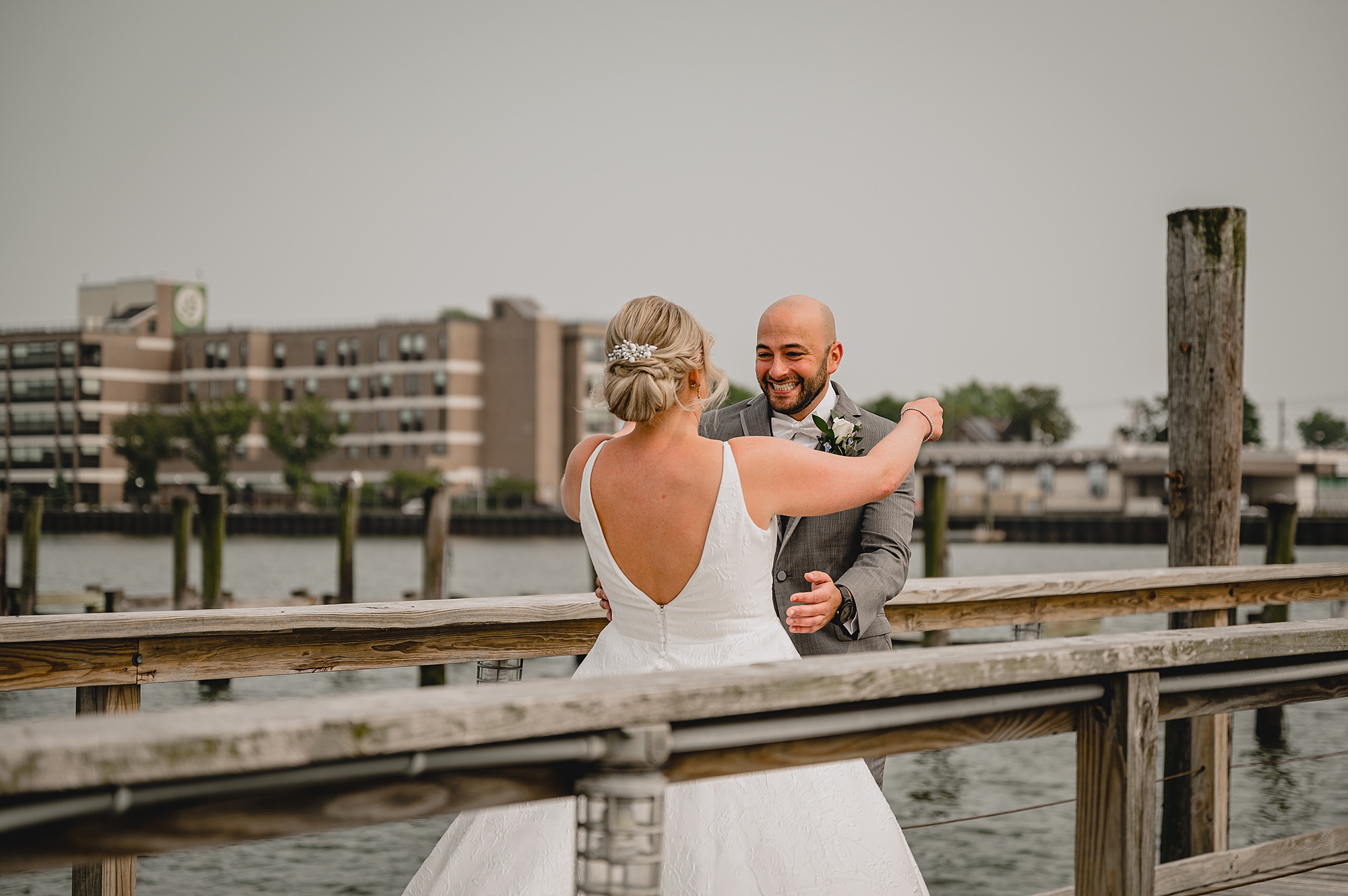 bride and groom hug on dock outside Bridgeview Yacht Club