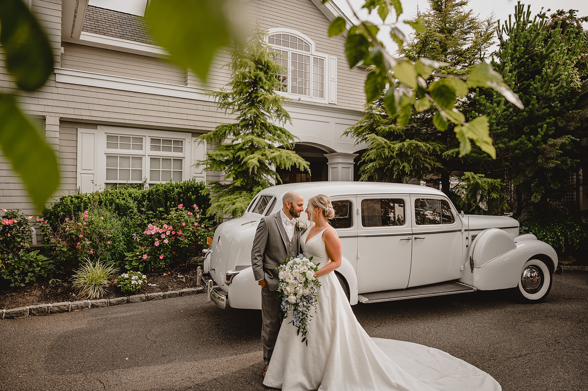 bride and groom hug by classic white Rolls Royce