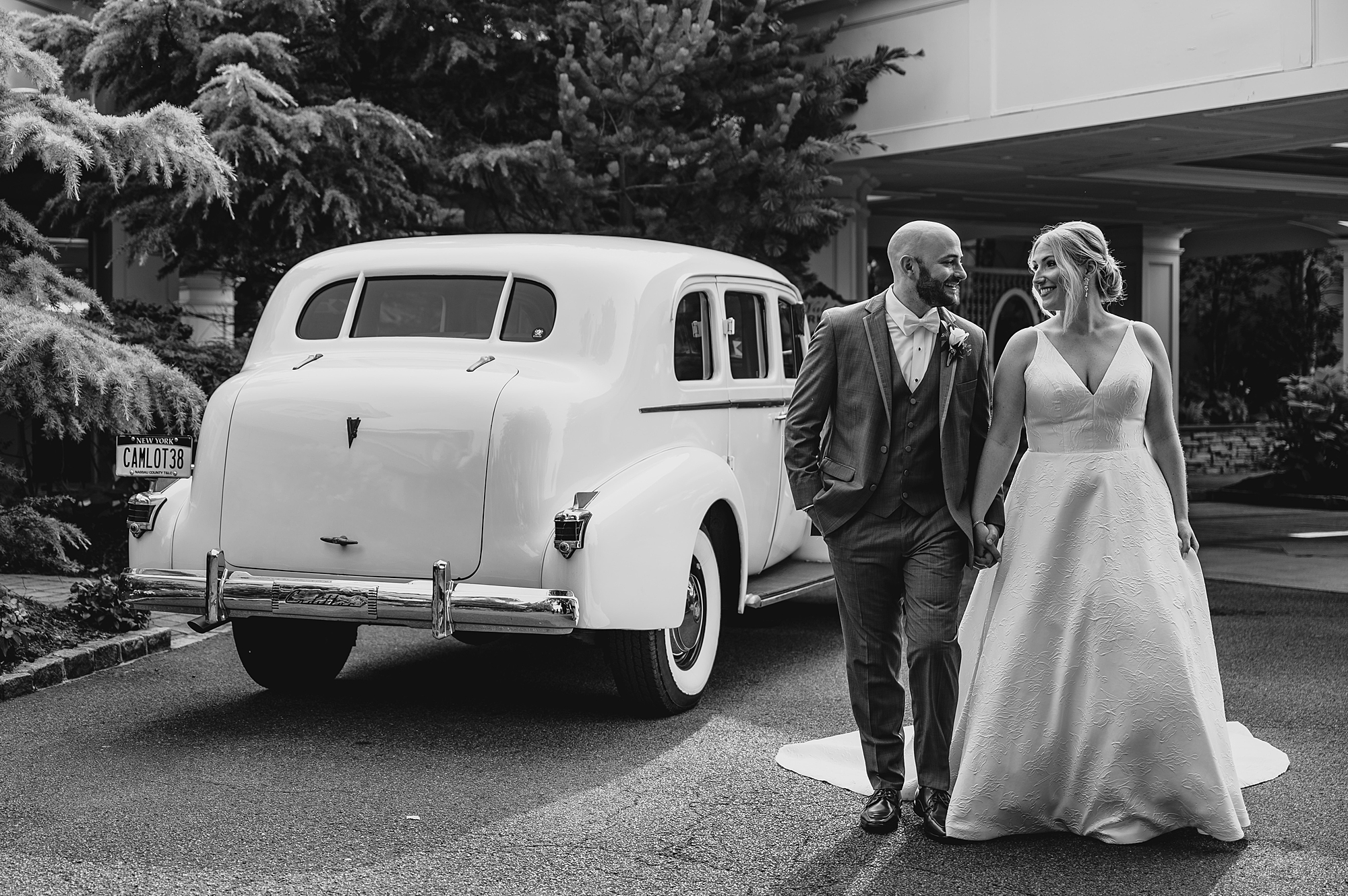 bride and groom hold hands walking by vintage car