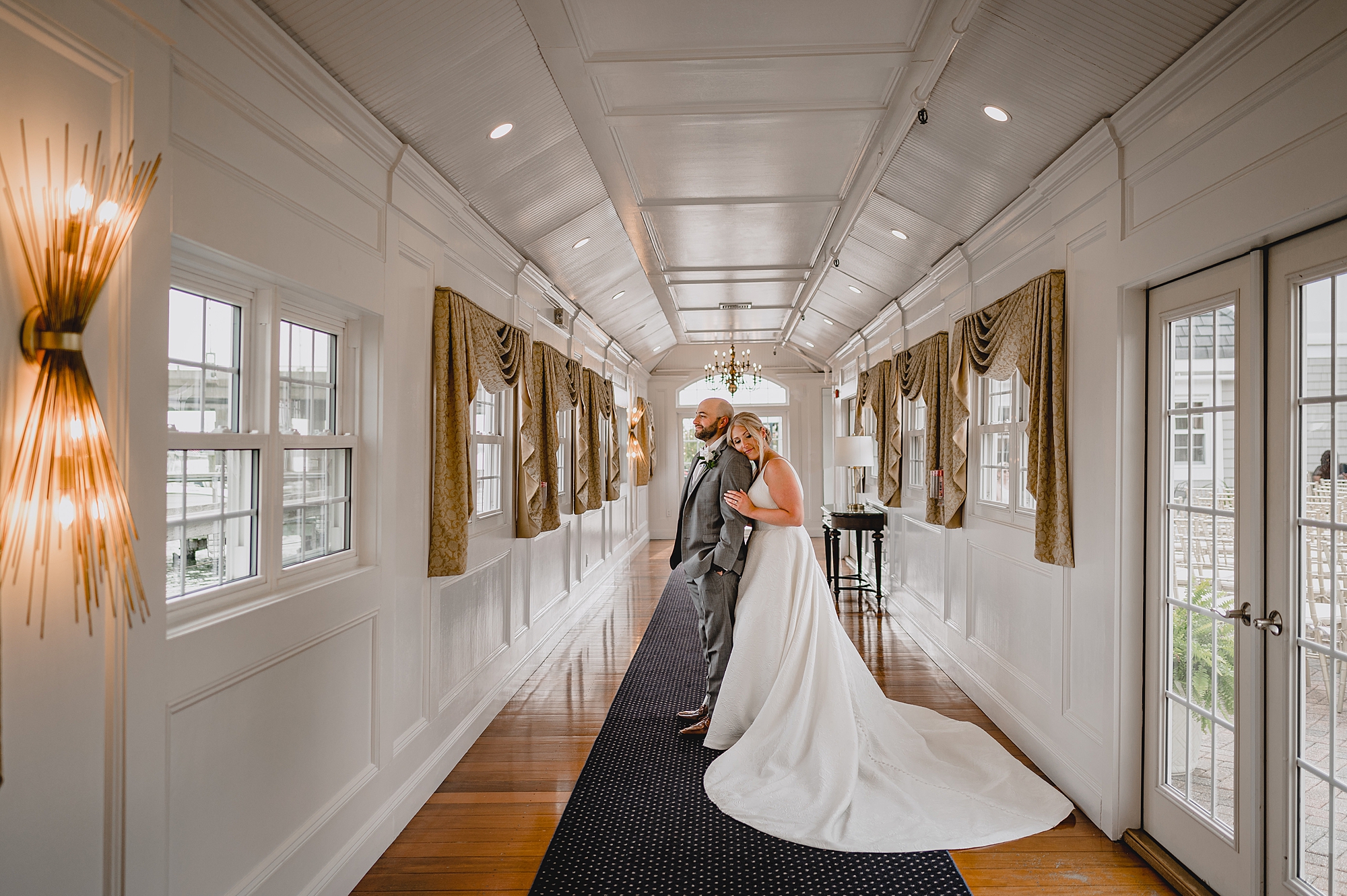 bride leans on groom's back inside Bridgeview Yacht Club