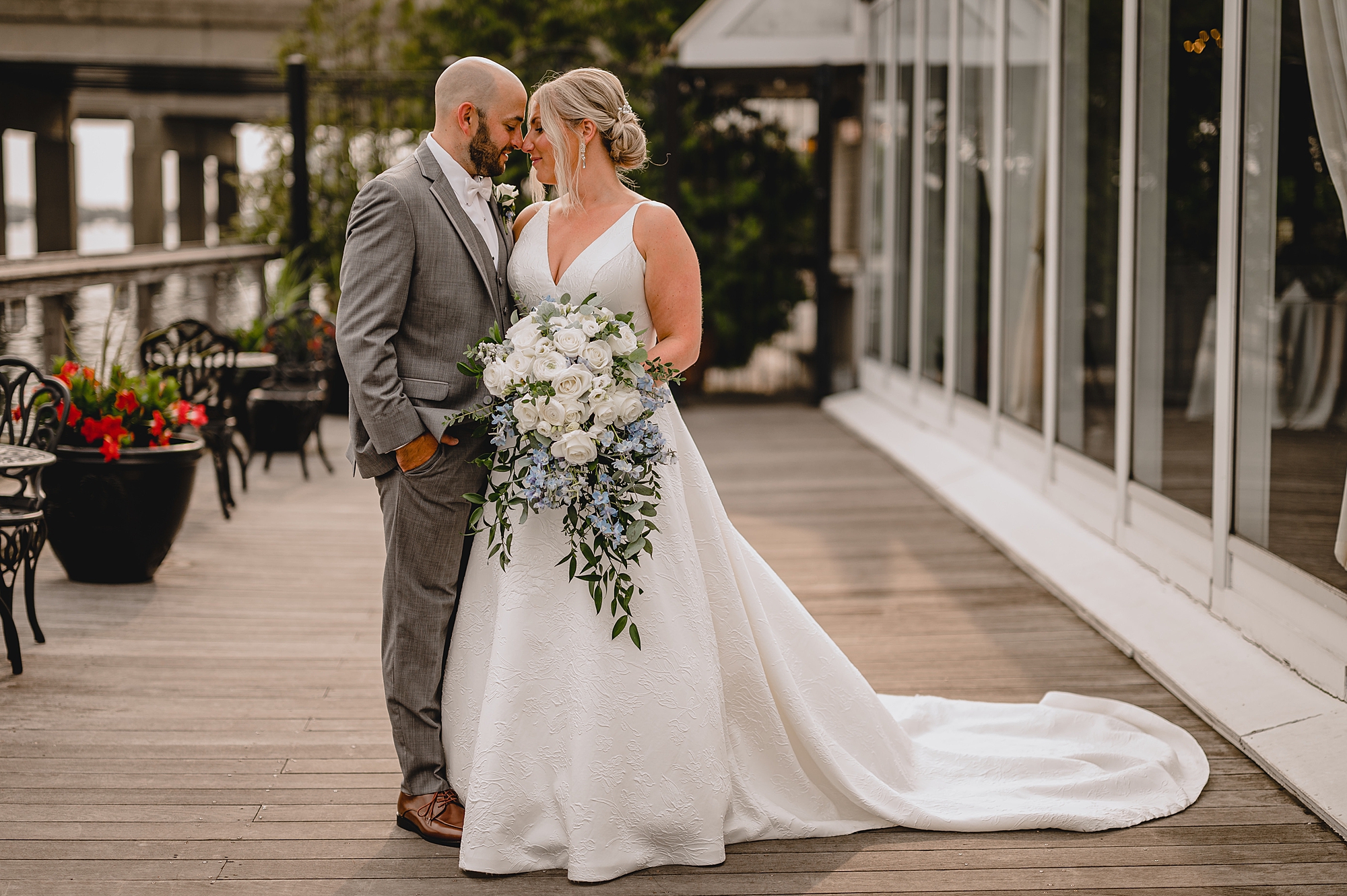 bride and groom stand together touching heads on outside patio at Bridgeview Yacht Club